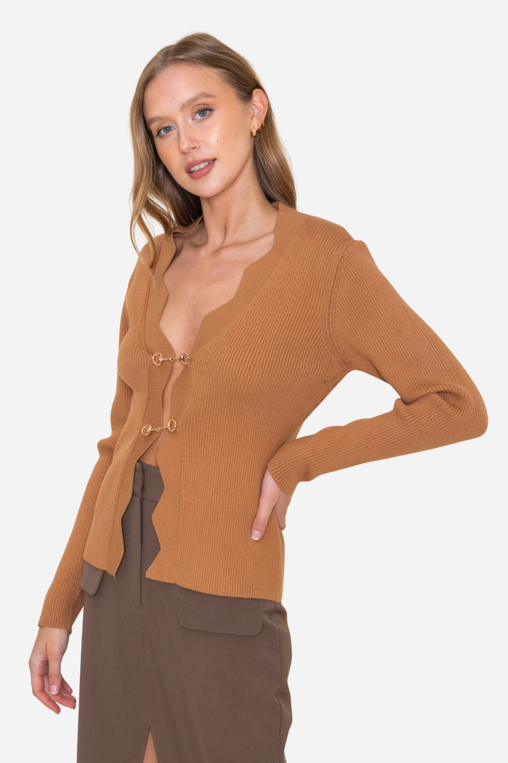 Camel-toned ribbed knit equestrian top featuring a deep scalloped neckline and two gold horsebit closures. Fitted long-sleeve cardigan-style top crafted from a poly/nylon blend, combining timeless elegance with refined equestrian detailing—perfect for fall and winter equestrian fashion.