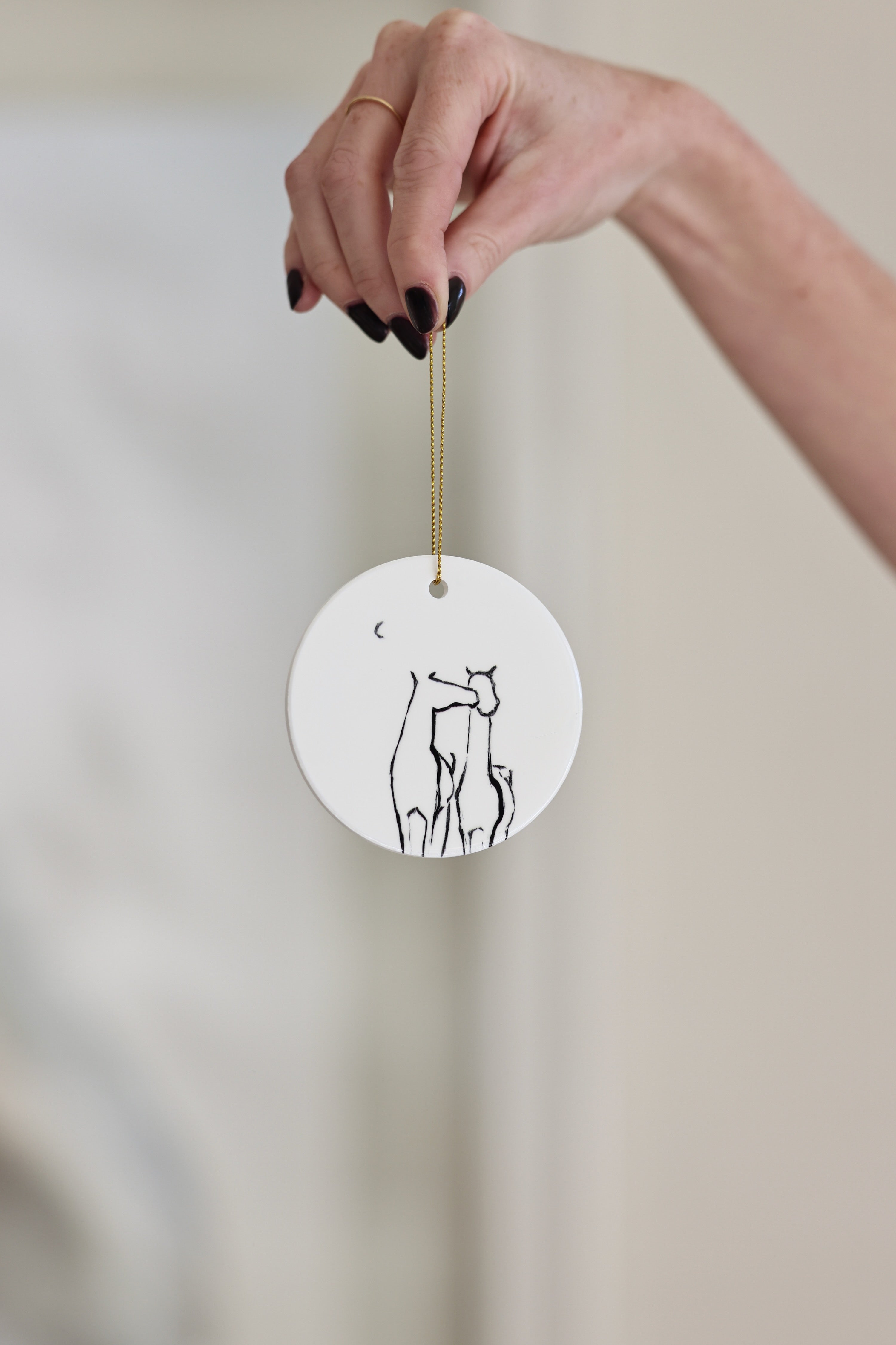 Besos Ornament — ceramic equestrian-inspired Christmas ornament featuring original horse artwork by Bettina, accented with gold tinsel. A charming horse-themed holiday decoration and thoughtful Christmas gift for equestrians and horse lovers. Made in the USA.