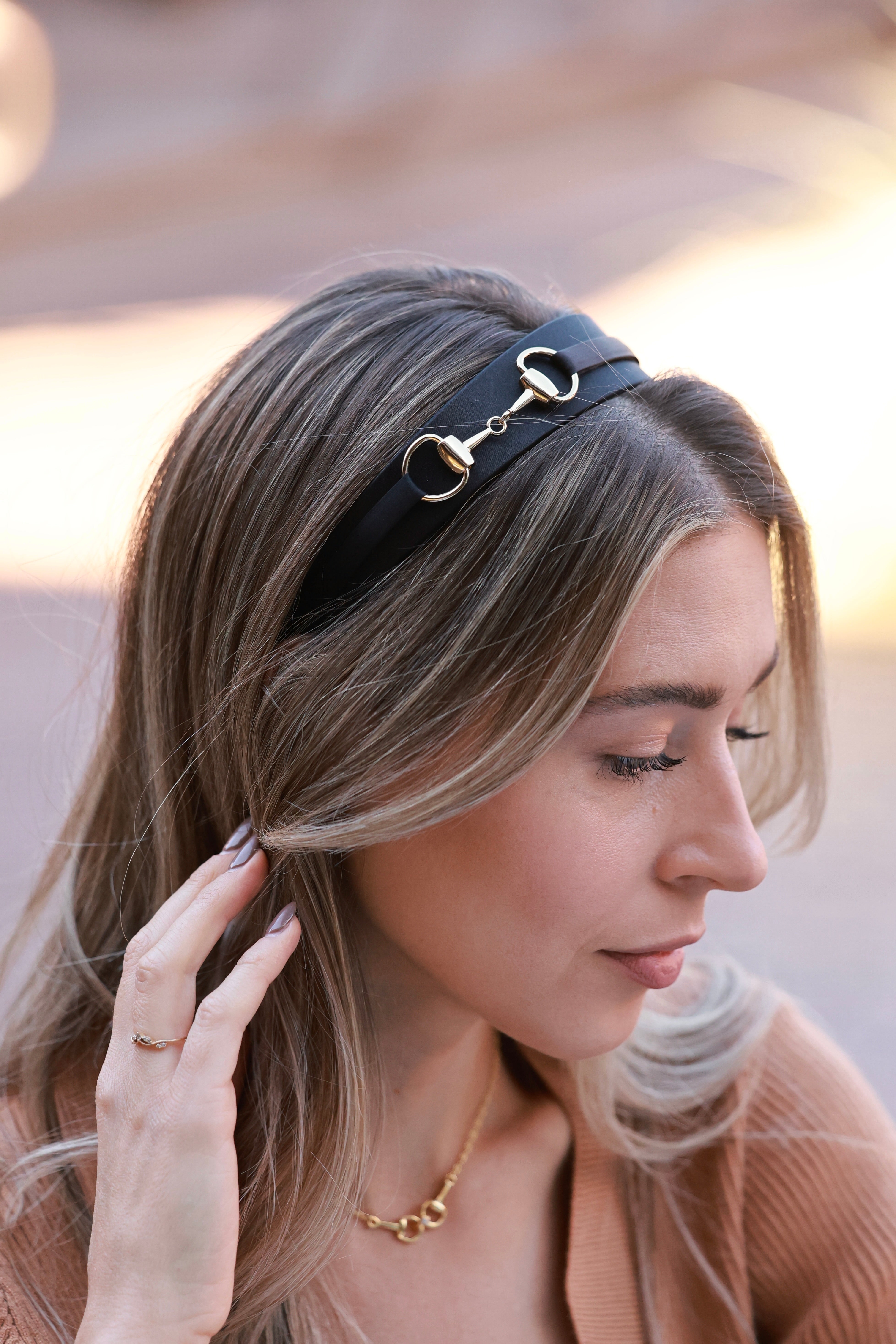 Elegant black silk charmeuse headband adorned with a gleaming gold snaffle bit detail. A timeless, equestrian-inspired accessory designed for comfort and all-day wear.