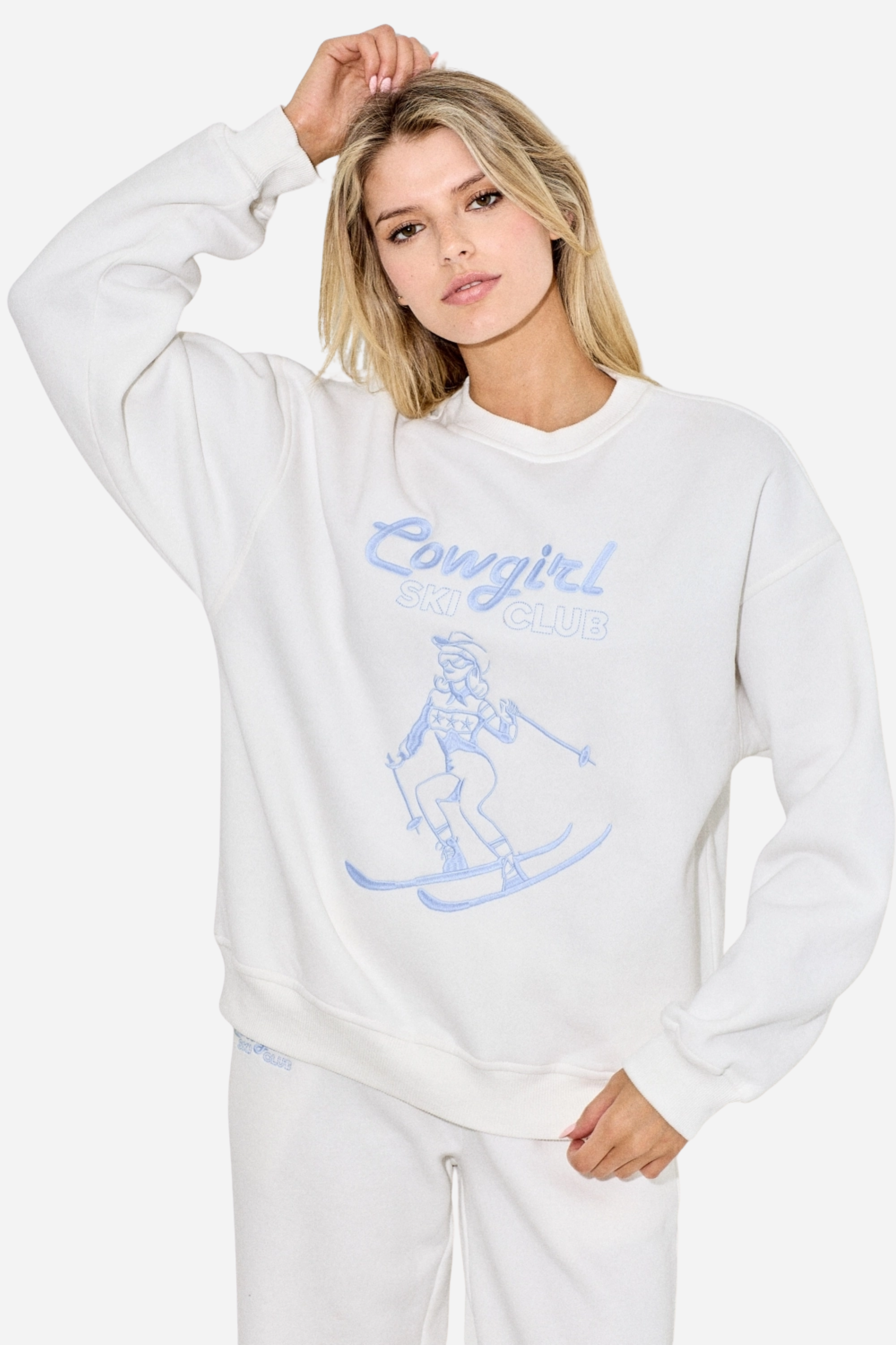 Cowgirl Ski Club Embroidered Sweatshirt — a cozy fleece pullover blending western charm with après-ski flair. Features a powder-blue embroidered skiing cowgirl graphic on soft cotton/poly fabric with ribbed cuffs, neckline, and hem. Relaxed fit for ultimate comfort and style, perfect for horse girls and western fashion lovers. western cowgirl embroidery detail, horse girl apparel, equestrian clothing, western riding sweatshirt, skiing cowgirl sweatshirt, cozy fleece pullover