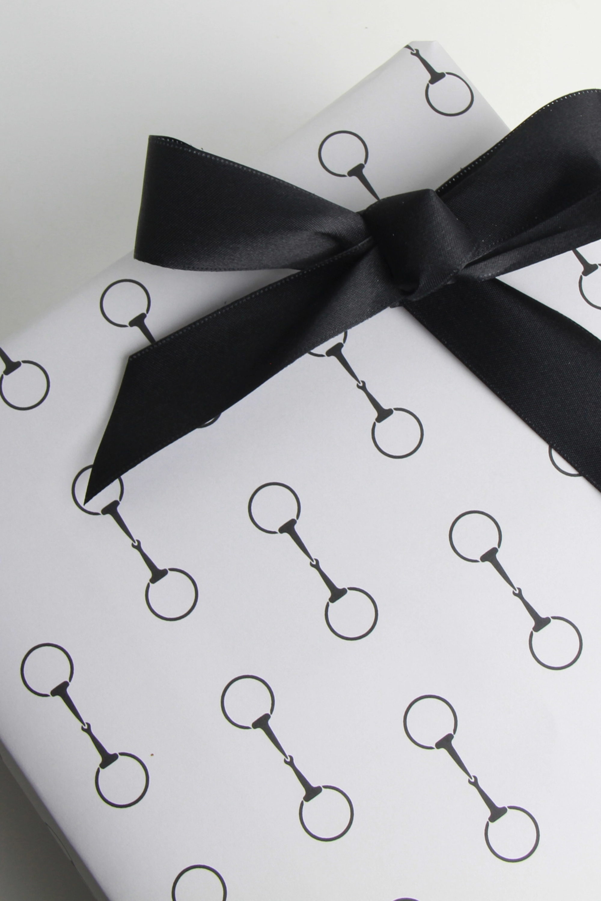 Elegant equestrian gift wrapping paper set featuring a repeating black horse bit pattern on premium textured white paper. Luxury horse-themed gift wrap sheets made in the USA—perfect for horse lovers, equestrian gifts, and stylish holiday packaging.