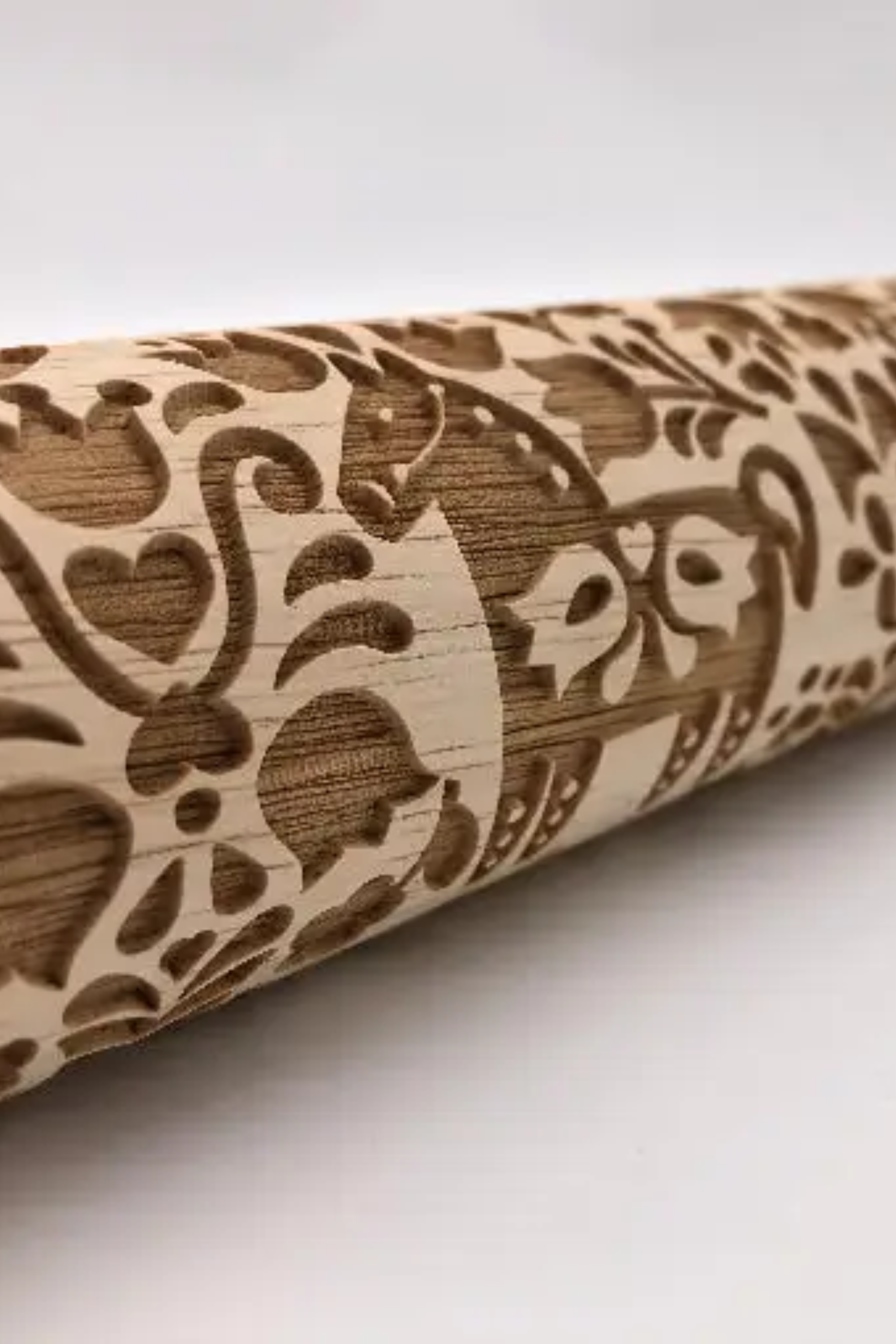 A Dala Horse Embossed Rolling Pin with an intricate floral pattern carved into its surface, designed for imprinting elegant Swedish-inspired motifs onto cookie dough, fondant, or craft materials. The rolling pin rests on a light wooden surface beside freshly embossed cookies and baking ingredients, showcasing its detailed craftsmanship and versatility for baking and crafting projects.