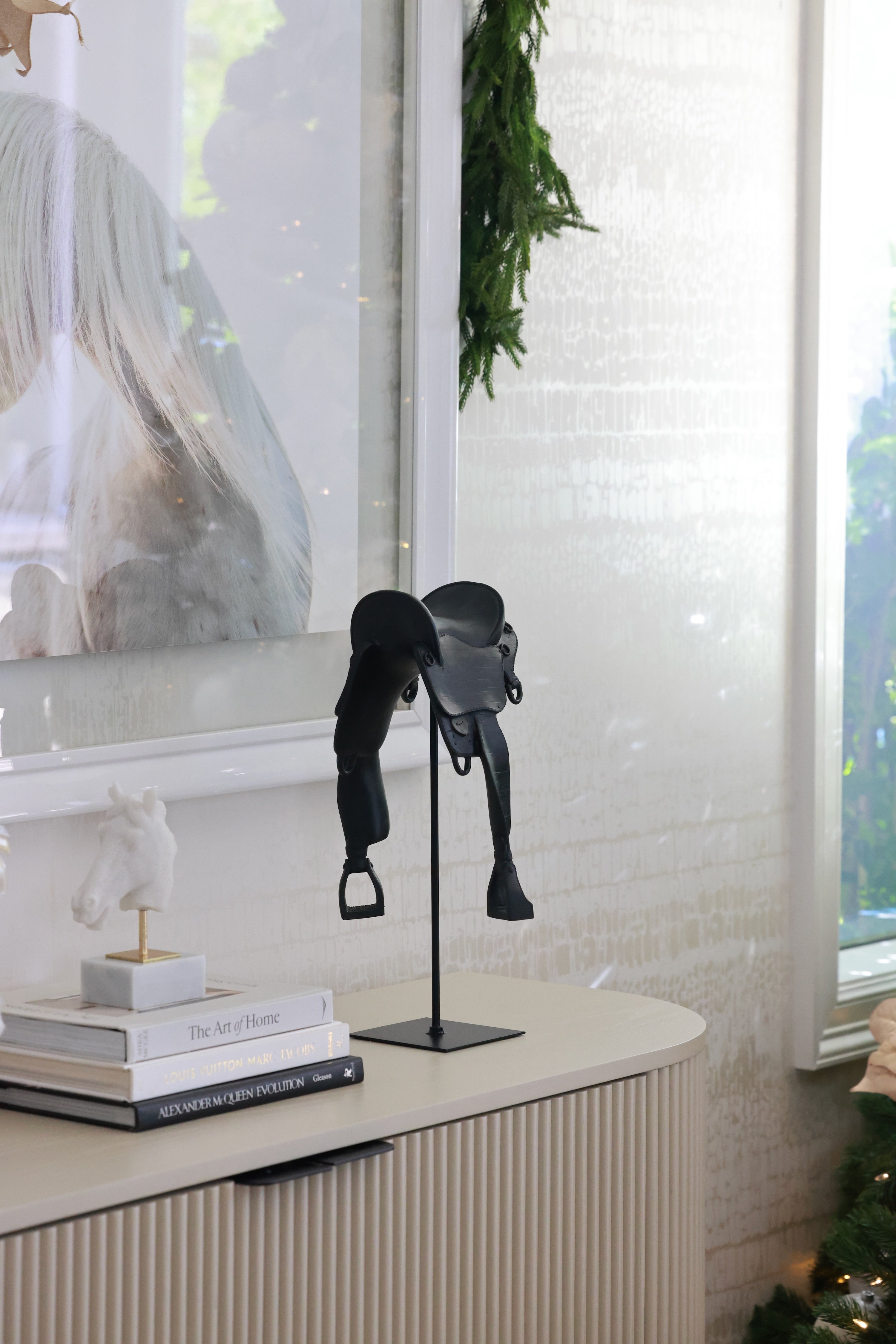 Black English-style horse saddle decor piece crafted from matte-finish resin and metal detailing. Mounted on a black metal stand with a square base, this modern equestrian sculpture captures the elegance of traditional riding saddles and adds a bold statement to home or office décor.
