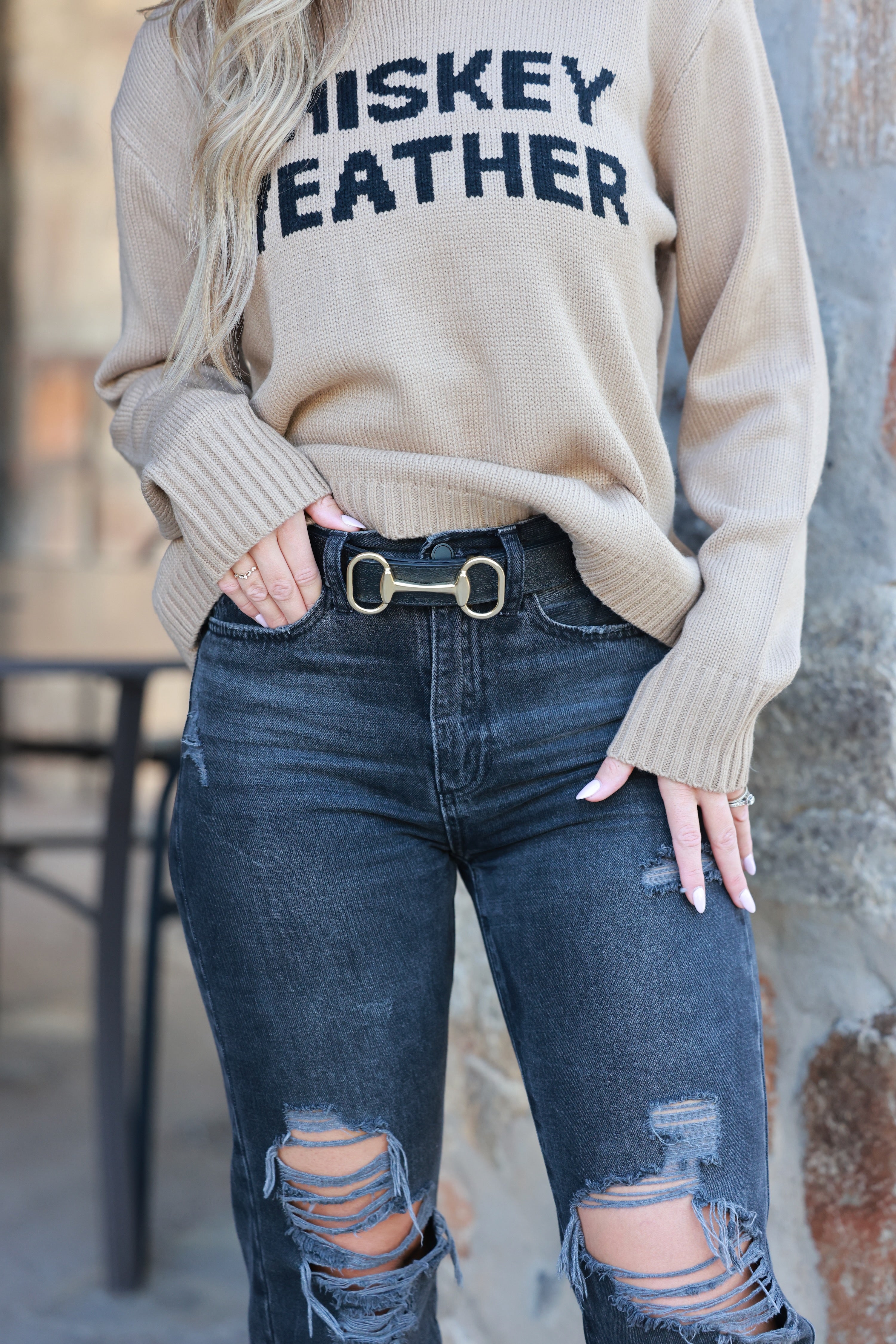 Person wearing a beige sweater with 'Whiskey Feather' text and ripped jeans. - equestrian accessory, horse themed belt, horse bit leather belt, accessories for horse girls