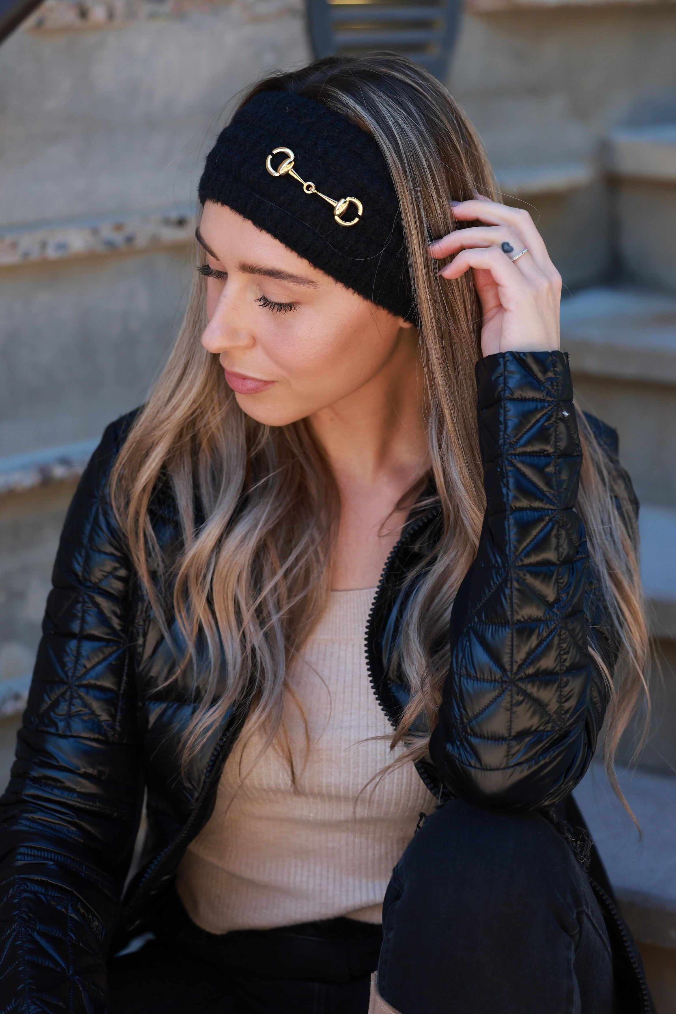 Black Elsie Knit Headband featuring soft, stretchy knit fabric and a gold bit accent. Comfortable, secure fit adds a touch of equestrian elegance to any cold-weather look.