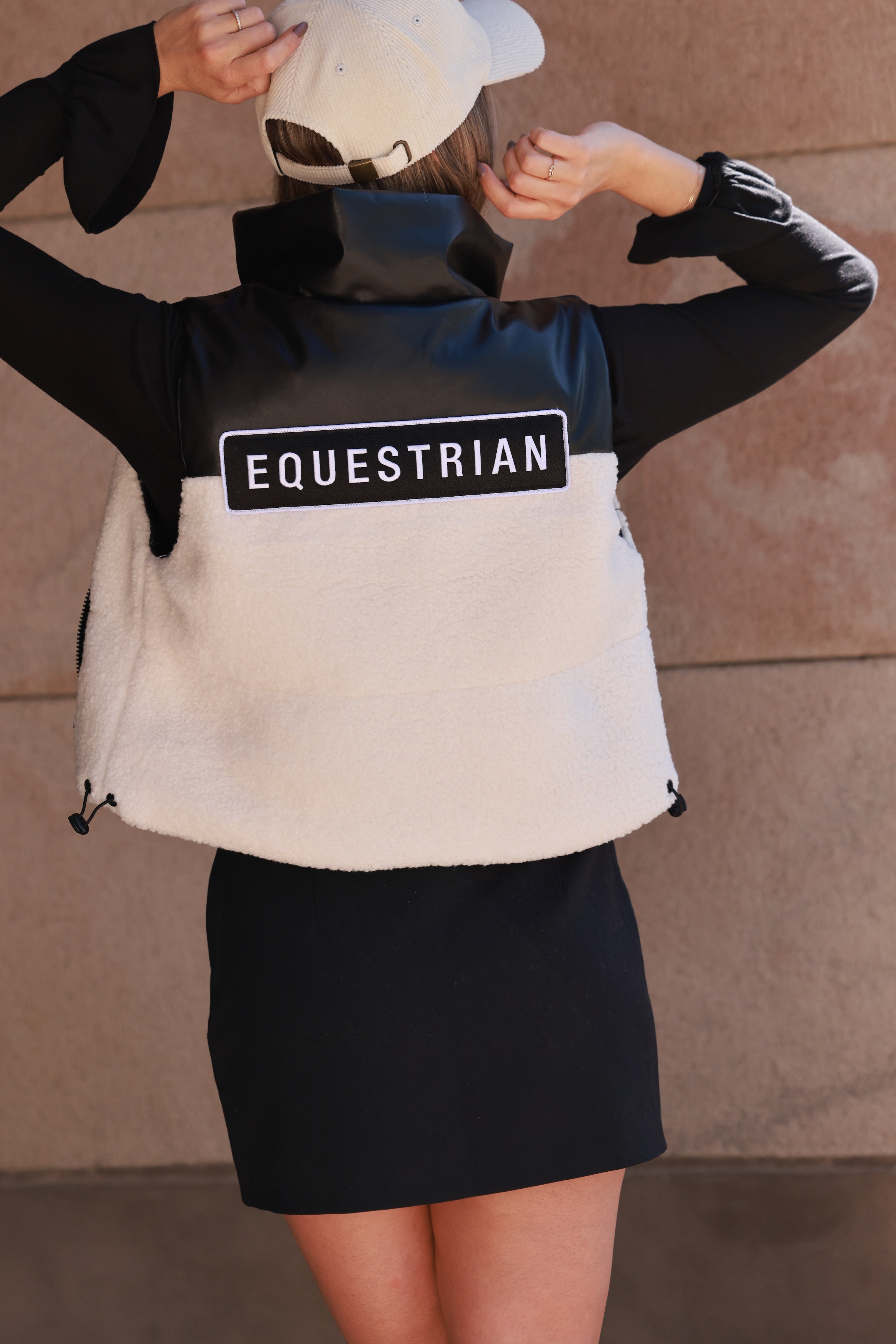 Stylish equestrian cropped puffer vest featuring contrasting sherpa and faux leather panels, embroidered equestrian patch on back, full zip front, and interior drawstring for a flattering fit — the ultimate trendy horse girl winter vest.