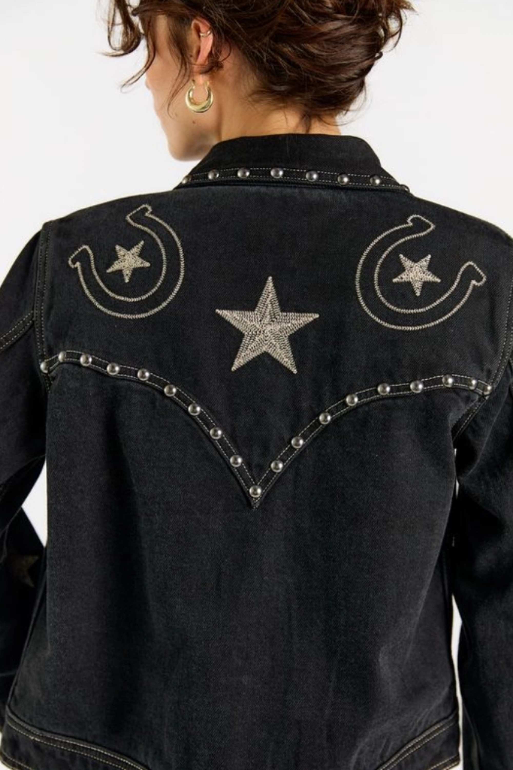 Black cotton denim jacket with all-over equestrian and western-inspired embroidery, including horseshoes and stars, accented with metallic rivet detailing.