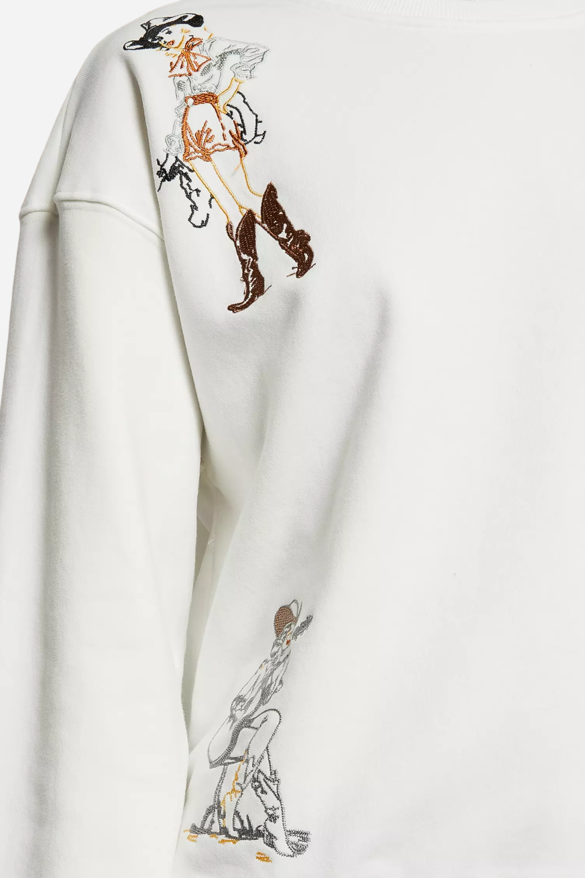 Woman wearing a white embroidered western cowgirl sweatshirt featuring horse and cowgirl-themed illustrations. This cozy equestrian clothing piece blends comfort and western riding style, perfect horse girl apparel with detailed embroidery for everyday wear.