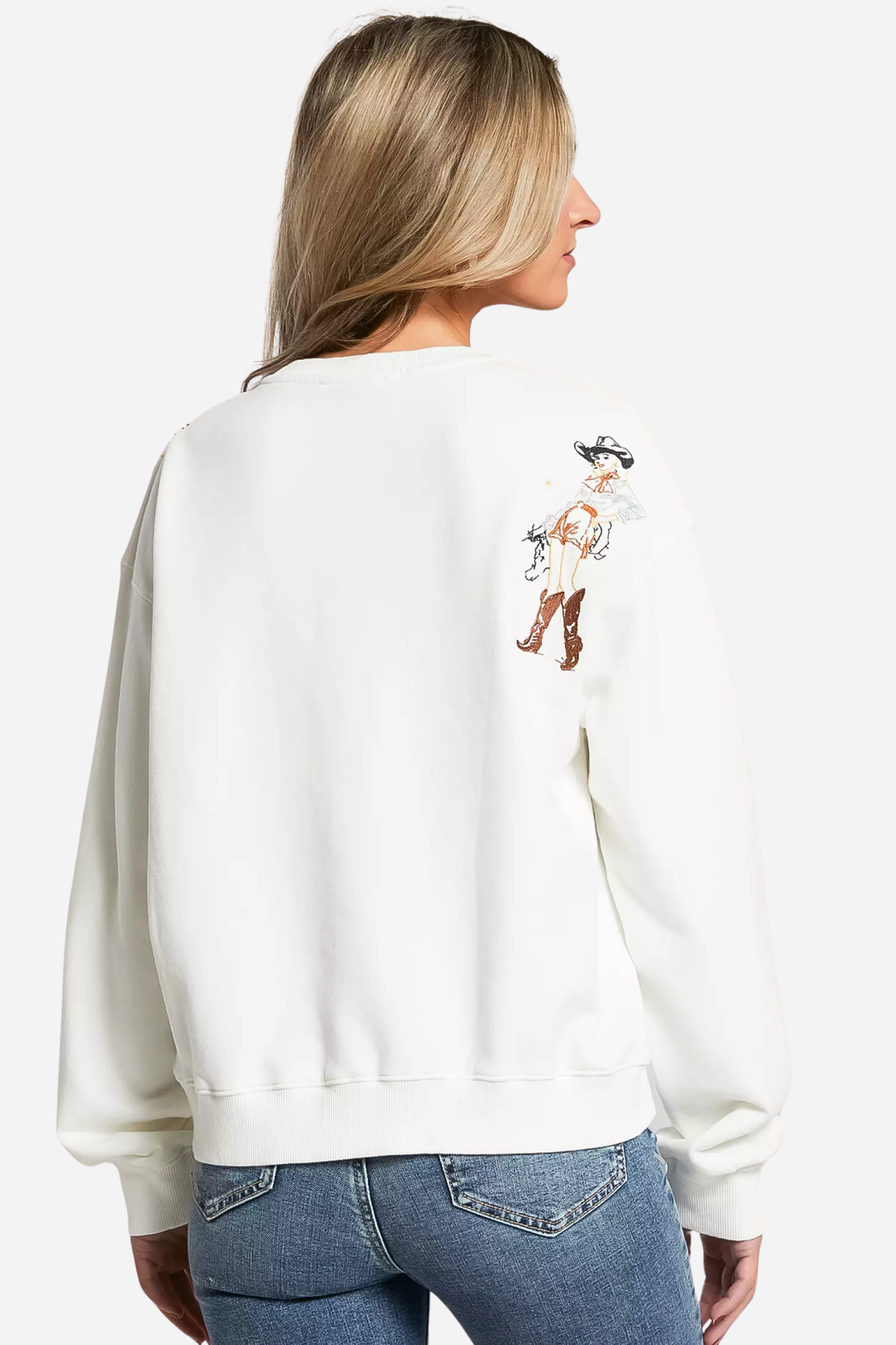 Woman wearing a white embroidered western cowgirl sweatshirt featuring horse and cowgirl-themed illustrations. This cozy equestrian clothing piece blends comfort and western riding style, perfect horse girl apparel with detailed embroidery for everyday wear.