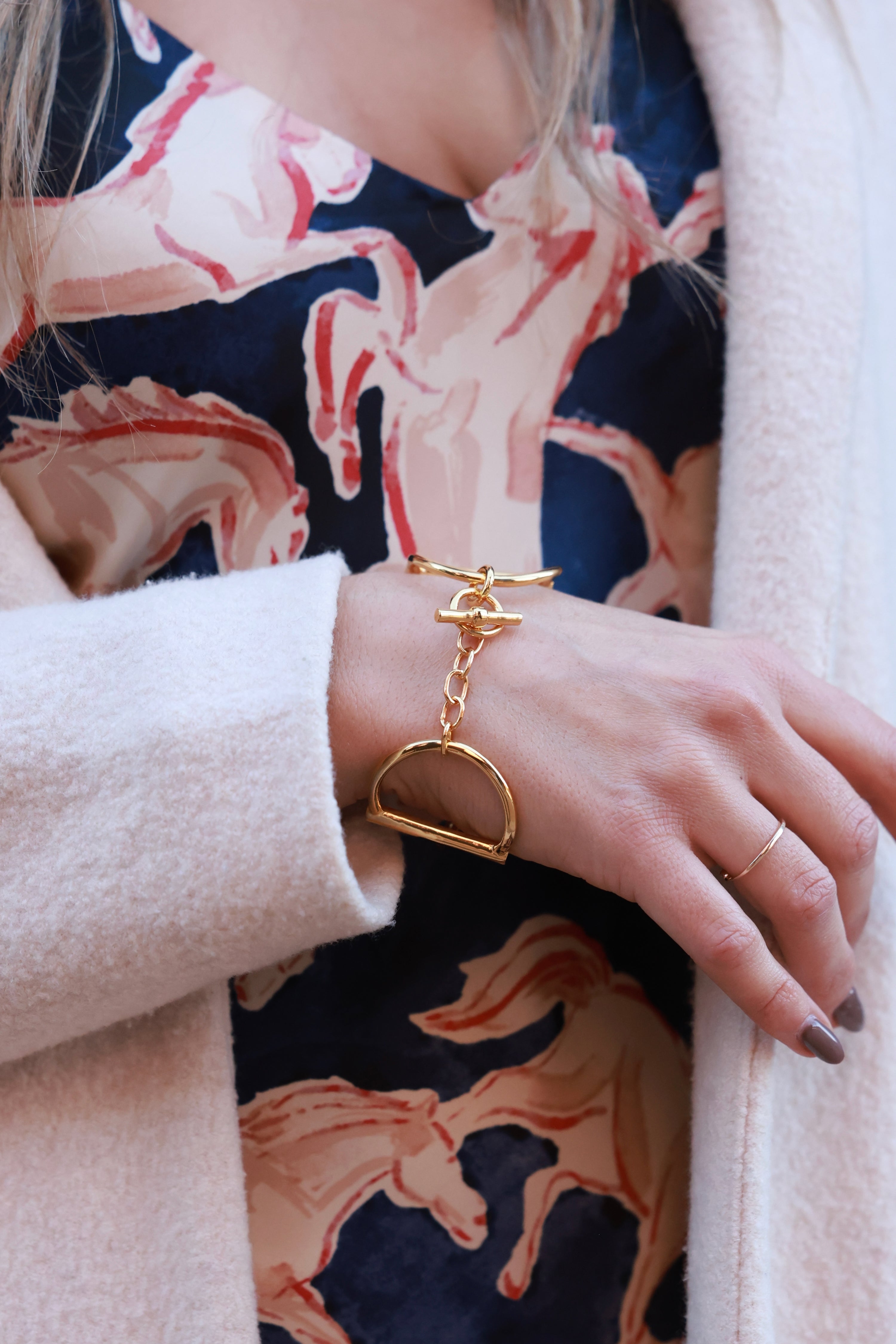 Heritage Horse Bit Gold Cuff — a bold, polished gold-over-brass bracelet with a sleek, modern open-triangle design, 1½-inch width, and iconic double horse-bit motif, connected by small links and secured with a signature toggle-and-ring clasp, elegantly curved to fit a 7½-inch wrist, photographed on a white background.