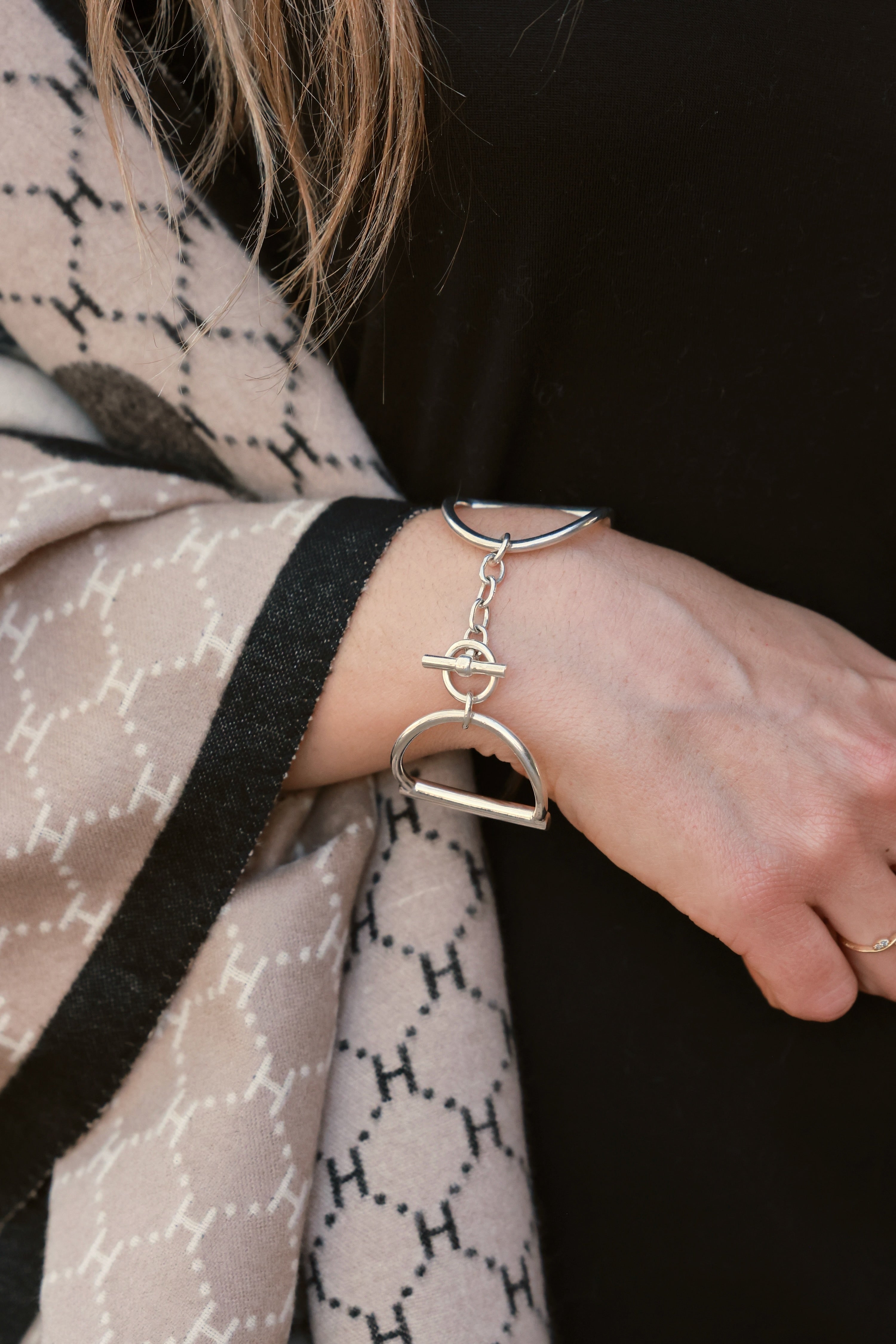 Heritage Bit Bracelet – Silver: a polished, hand-cast 925 sterling silver bracelet featuring geometric shapes and interlocking loops, bold 1½-inch width, and iconic double horse-bit design. Linked by a delicate chain with a signature toggle-and-ring clasp, elegantly curved to fit a 7½-inch wrist, showcasing a modern, minimalist, yet substantial equestrian style.