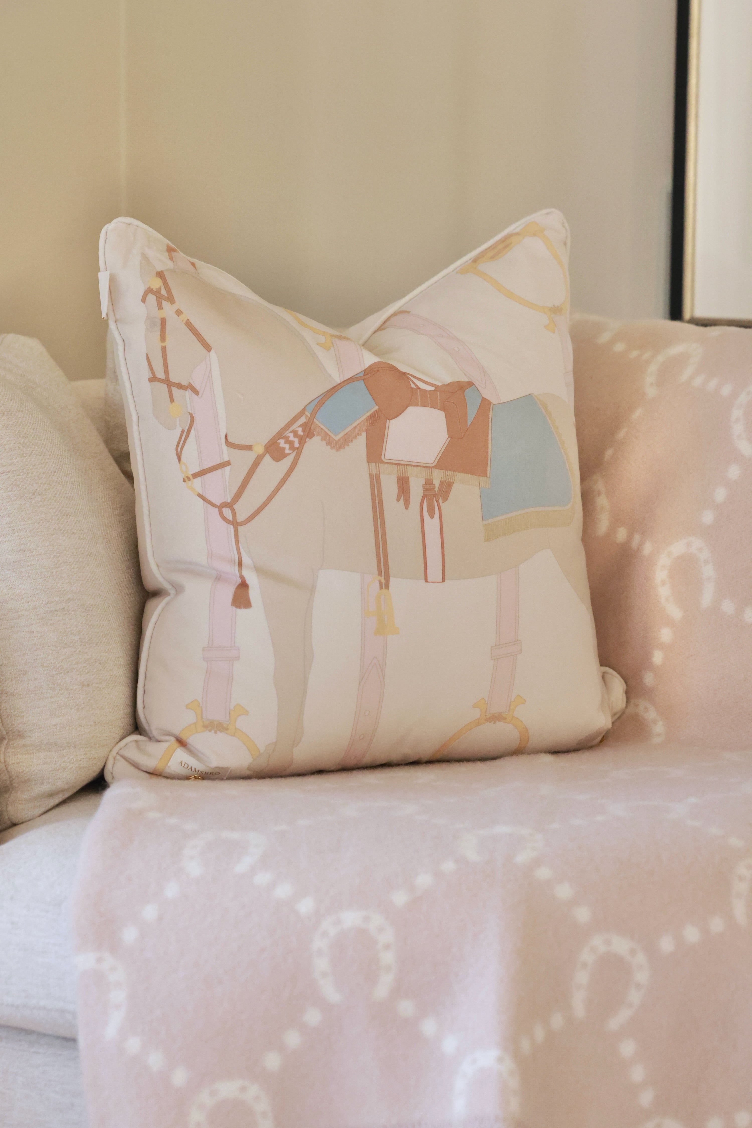 Heritage Horse pastel velvet pillow with equestrian-inspired design, luxury home décor cushion in off-white and beige tones, soft feather-filled insert, perfect for living rooms, bedrooms, or tack rooms. Decorative pillow with a soft brown horse design, featuring a blue and brown saddle. The background is light beige with subtle equestrian-themed accents.