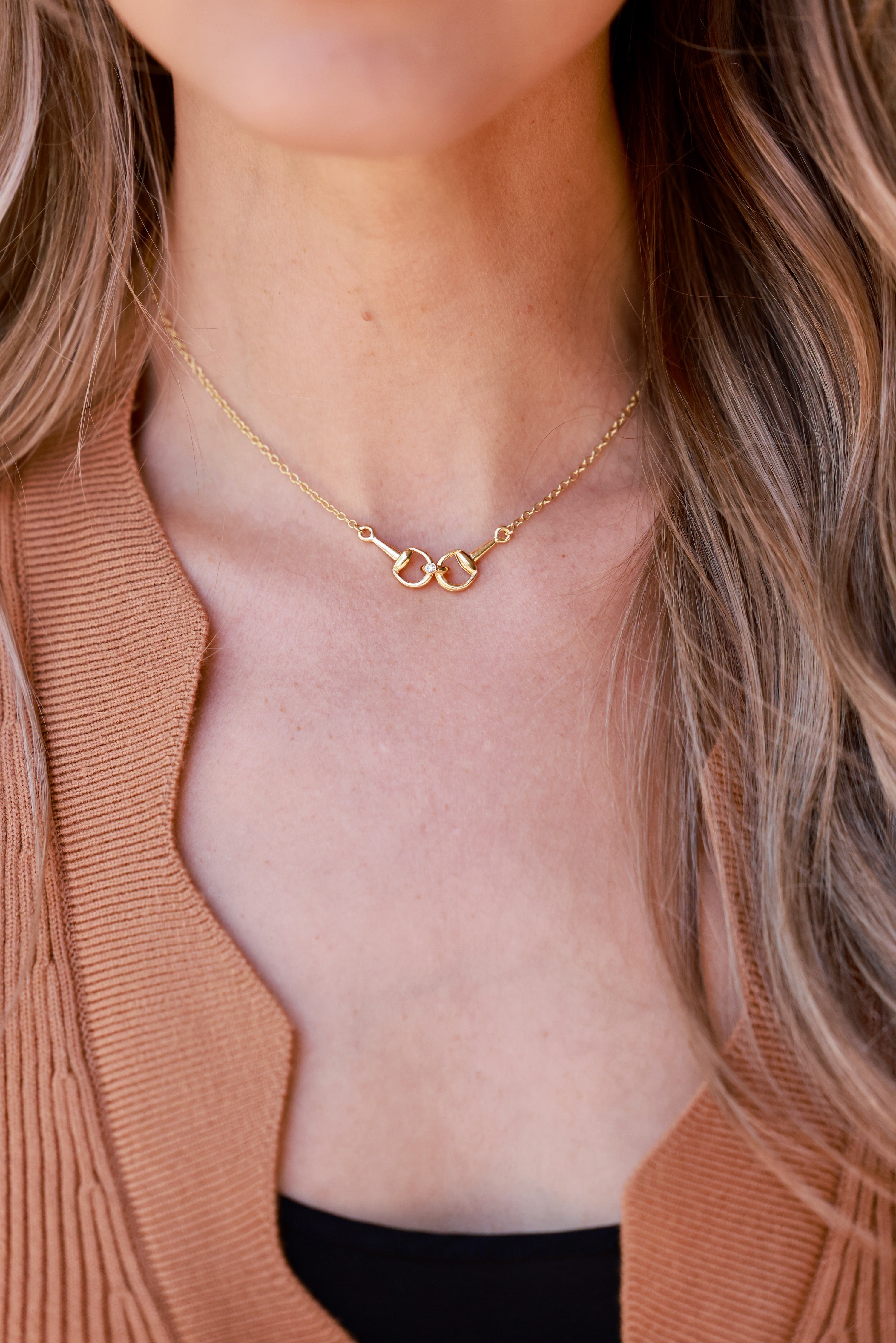 Close-up of a person wearing a gold necklace with a neutral background - equestrian inspired jewelry, horse girl accessory, horseshoe pendant necklace, dainty equestrian jewelry, small gifts for horse lovers