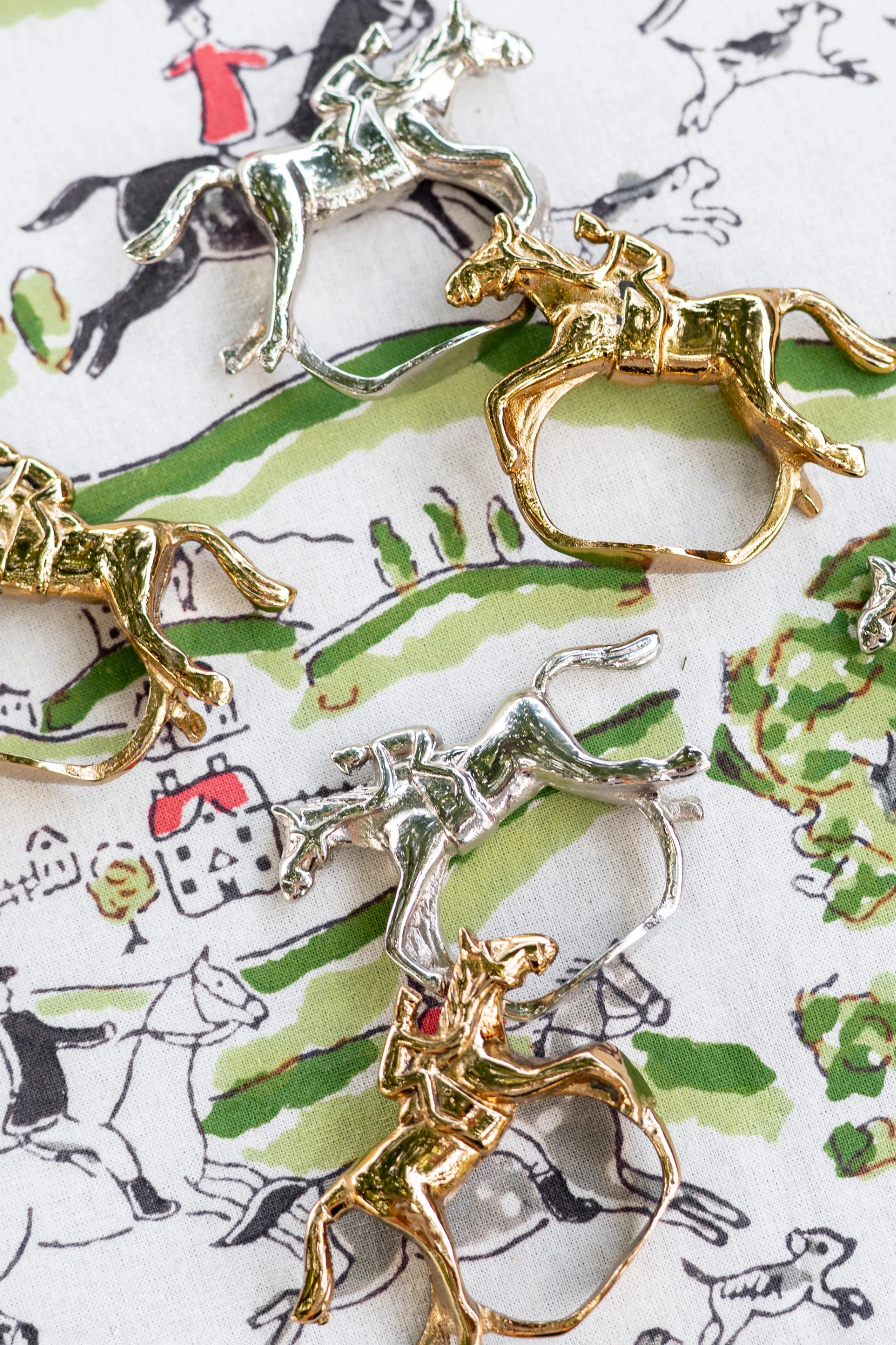 Pomegranate Jockey Napkin Ring Set - Gold Bring a touch of luxury to your table with the Gold Jockey Napkin Rings. This set of four features a stunning horse & jockey design that shines at every gathering. Ideal for formal dinners or casual brunches, these napkin rings are the perfect accessory to elevate your dining decor.