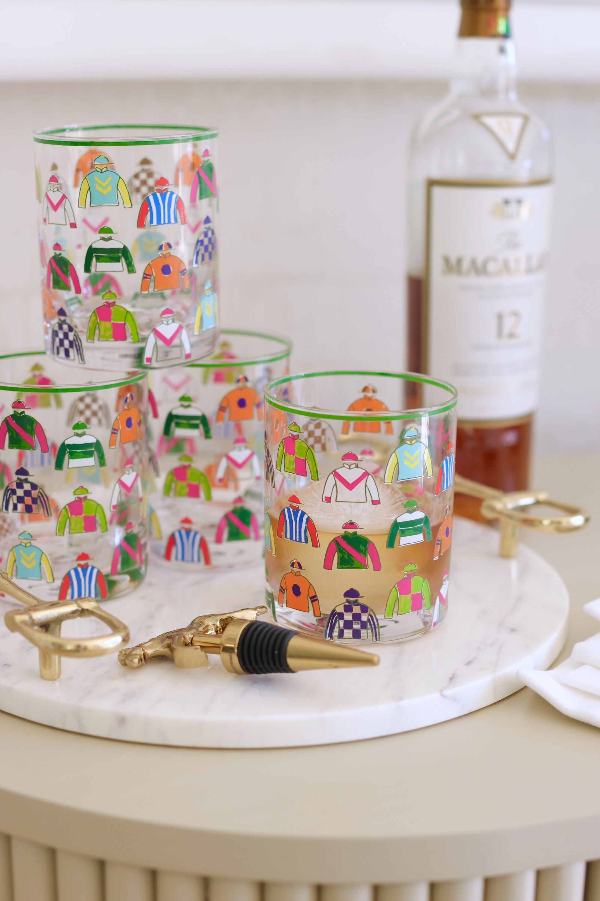 Pomegranate Jockey Silks Short Drinking Glass Set Get ready for the races with the Jockey Silks Bourbon Glass set. Each glass in this set of four is wrapped in a vibrant parade of racing silks, reminiscent of Derby Day at Churchill Downs or a crisp autumn afternoon at Keeneland. Whether you’ve got a colt in the running or you’re just here for the juleps, these glasses are a sure bet for any gathering.