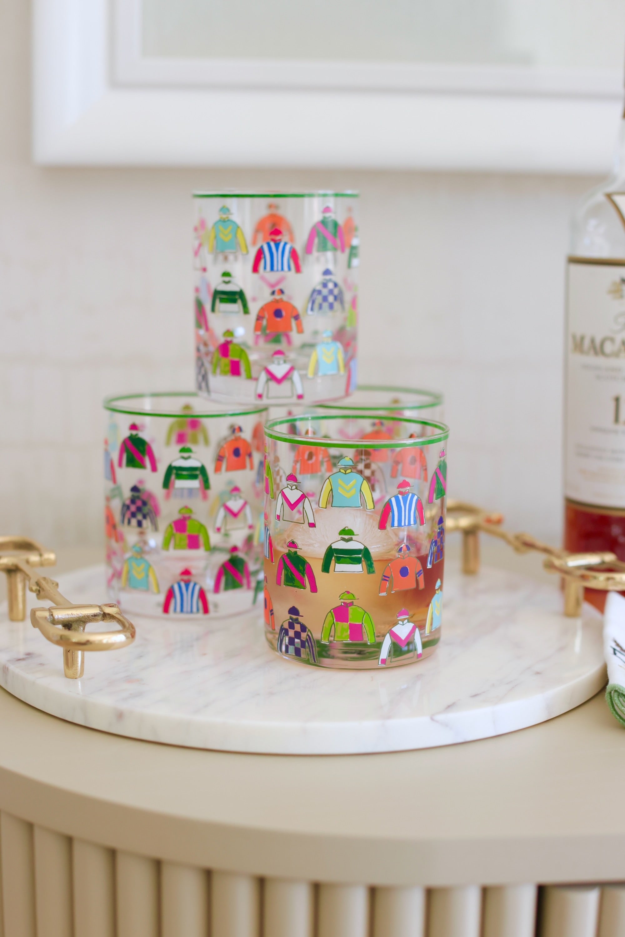 Pomegranate Jockey Silks Short Drinking Glass Set Get ready for the races with the Jockey Silks Bourbon Glass set. Each glass in this set of four is wrapped in a vibrant parade of racing silks, reminiscent of Derby Day at Churchill Downs or a crisp autumn afternoon at Keeneland. Whether you’ve got a colt in the running or you’re just here for the juleps, these glasses are a sure bet for any gathering.