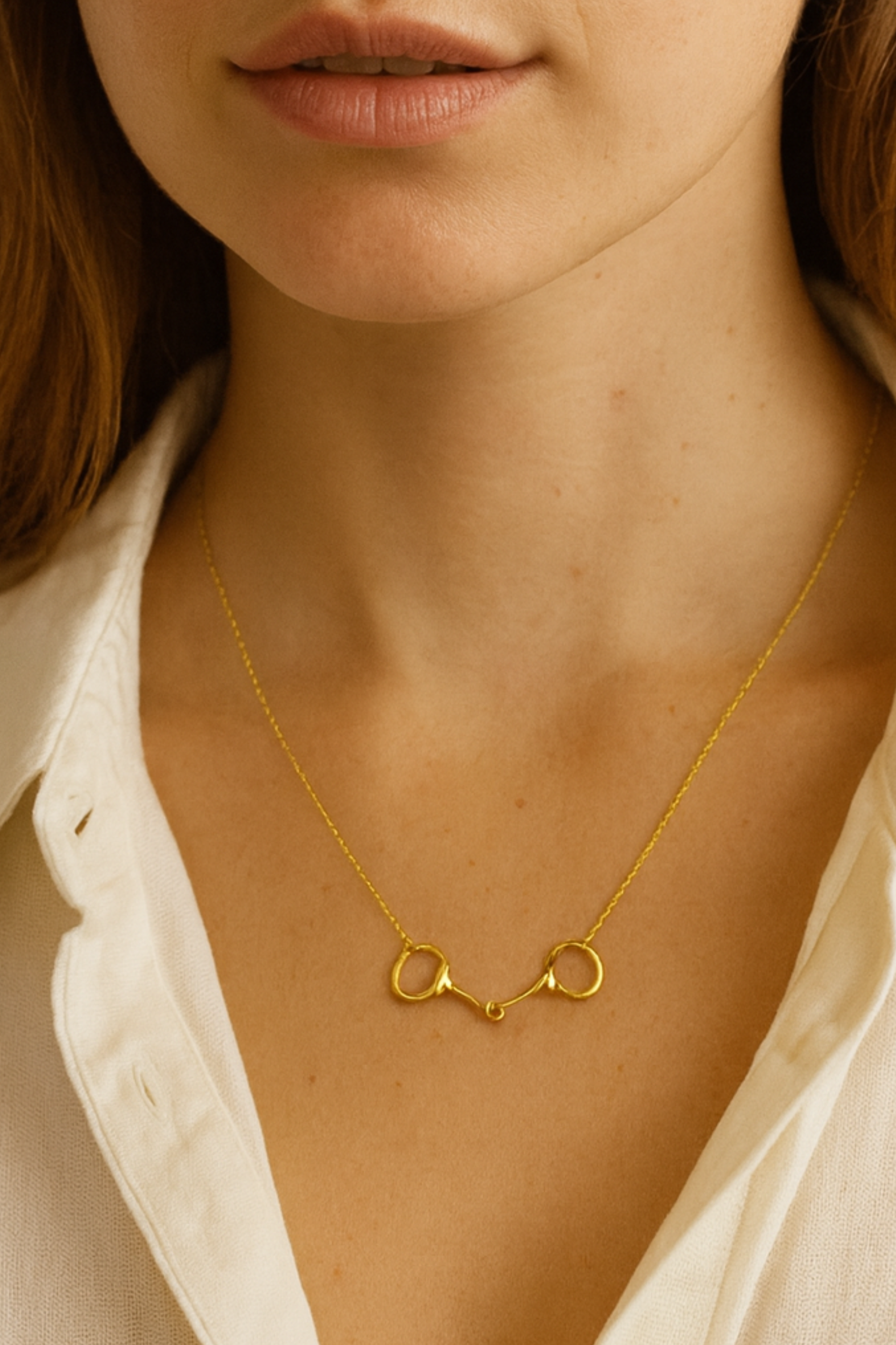 Minimalist gold necklace with a dainty horse bit pendant.