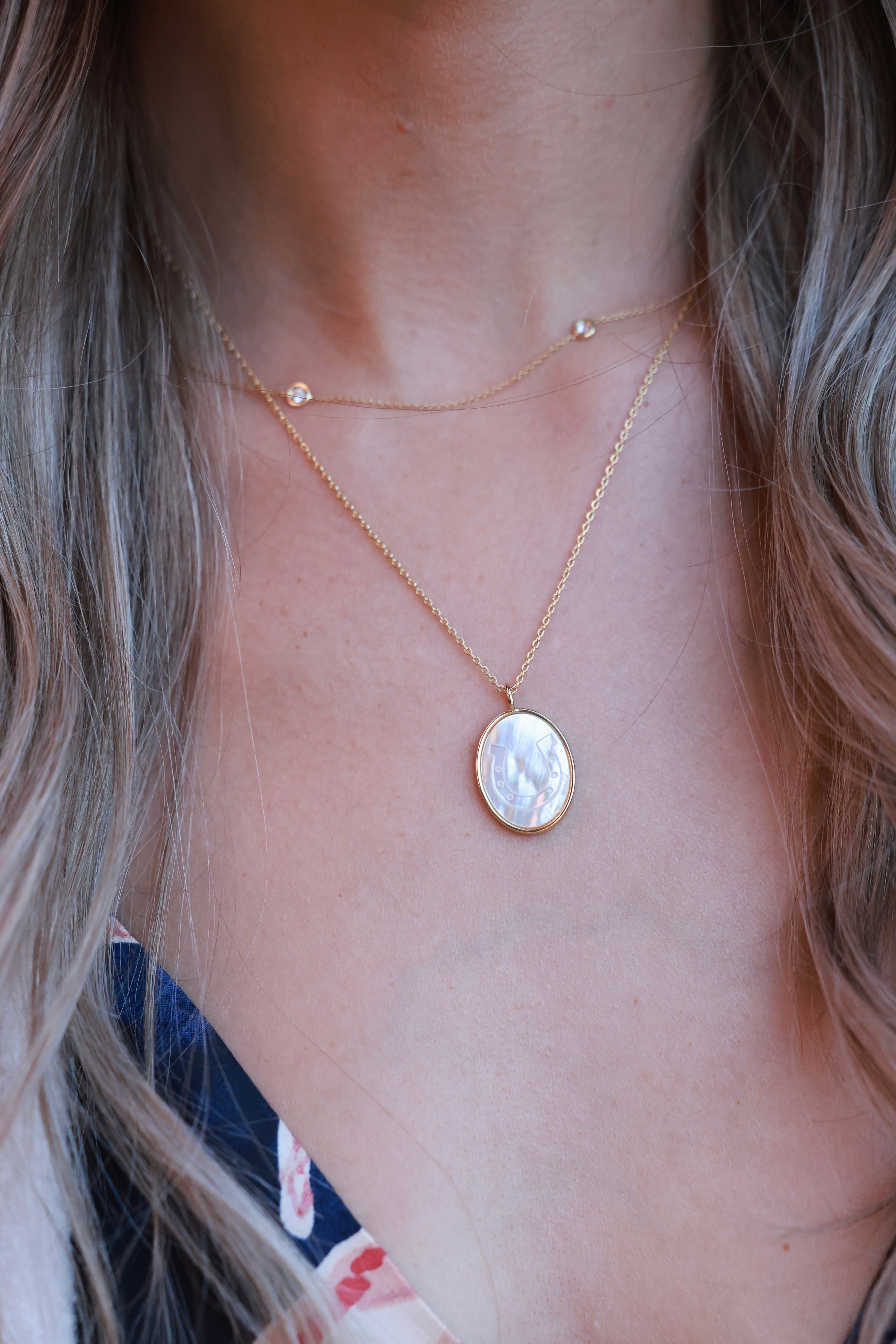 Lucky Cowgirl Necklace featuring a delicate gold-framed pendant with an intricately etched horseshoe design set in luminous mother-of-pearl. 18-inch plated brass chain with .95-inch pendant — a dainty equestrian-inspired accessory perfect for horse lovers.