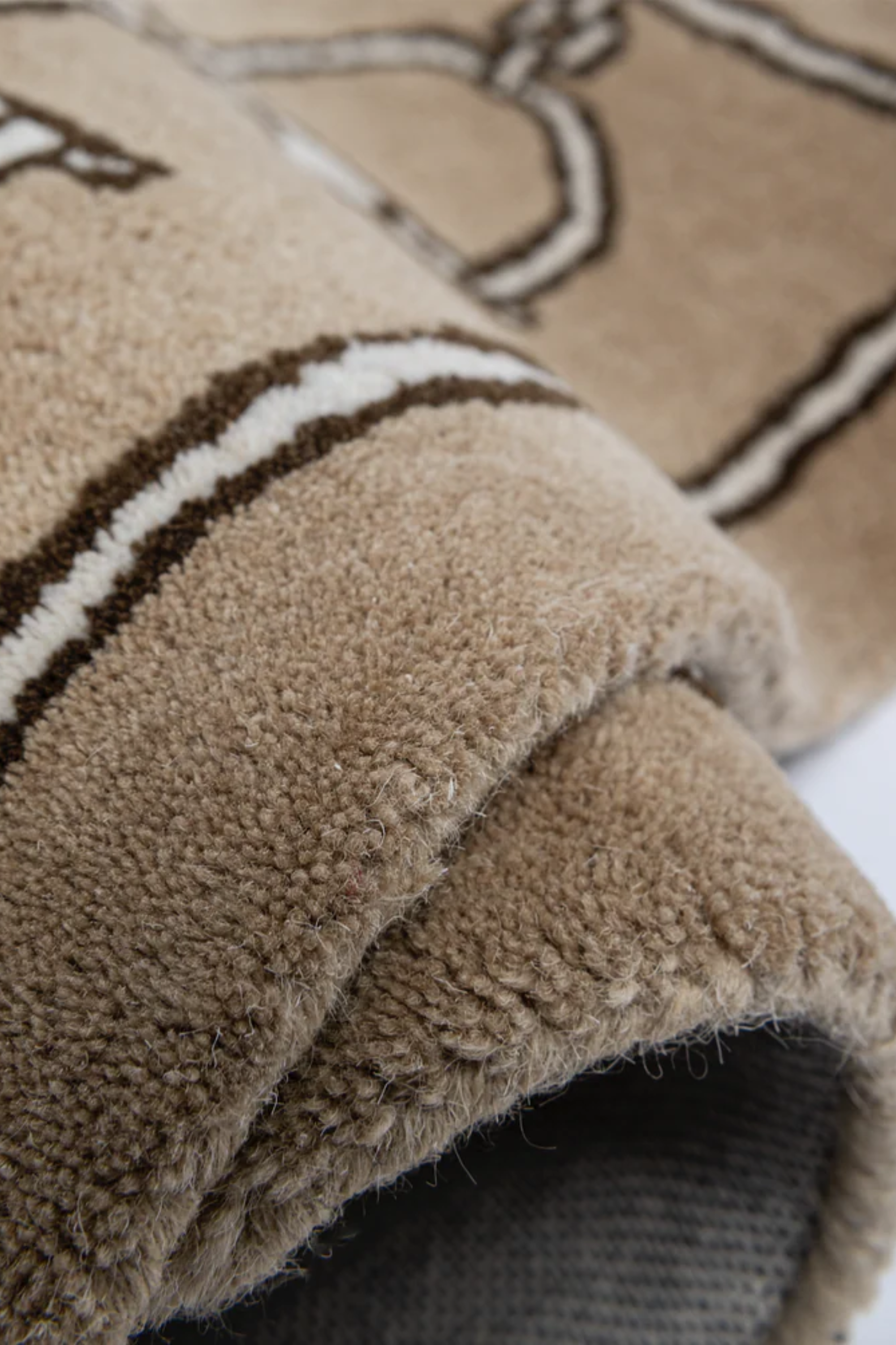 Tan rug featuring a pattern of dark brown horse bits aligned vertically in two columns with a matching dark brown border. Simple and elegant design. equestrian inspired snaffle bit print rug horse themed home decor