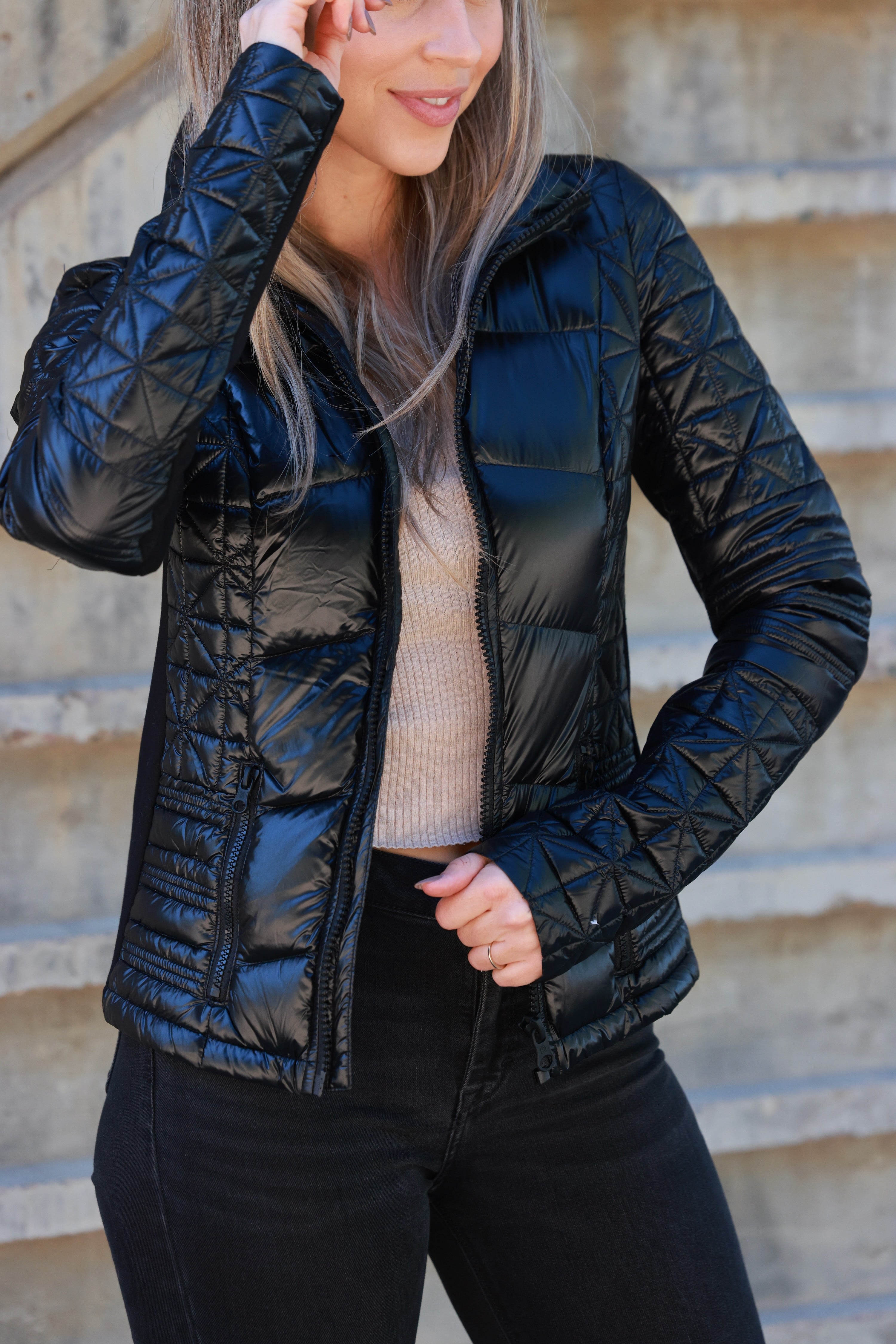 Woman wearing a black quilted jacket against a plain background - Packable puffer jacket, Lightweight down jacket, Black athletic outerwear, Travel-friendly puffer coat, Stylish winter layering