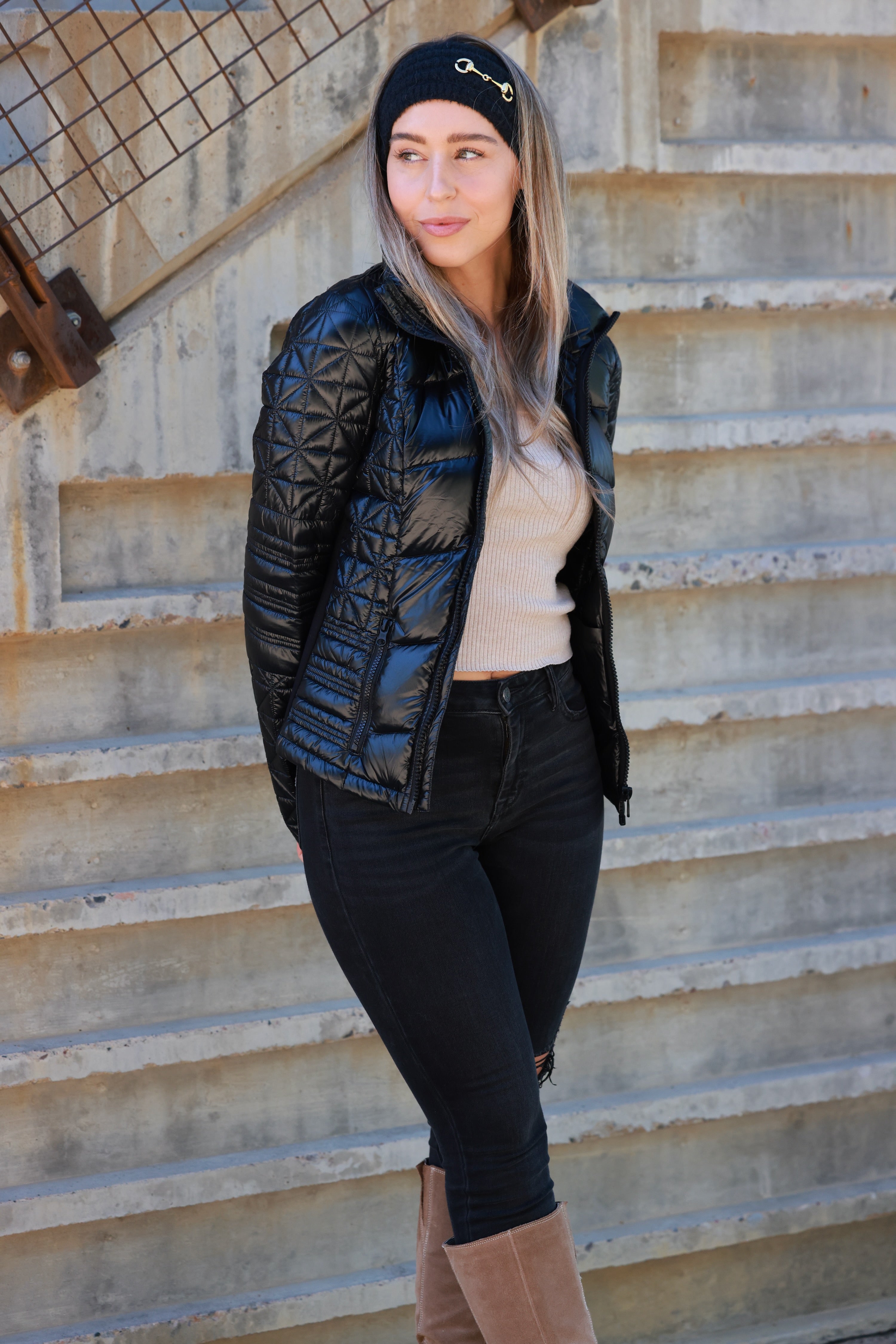 Woman wearing a black quilted jacket against a plain background - Packable puffer jacket, Lightweight down jacket, Black athletic outerwear, Travel-friendly puffer coat, Stylish winter layering