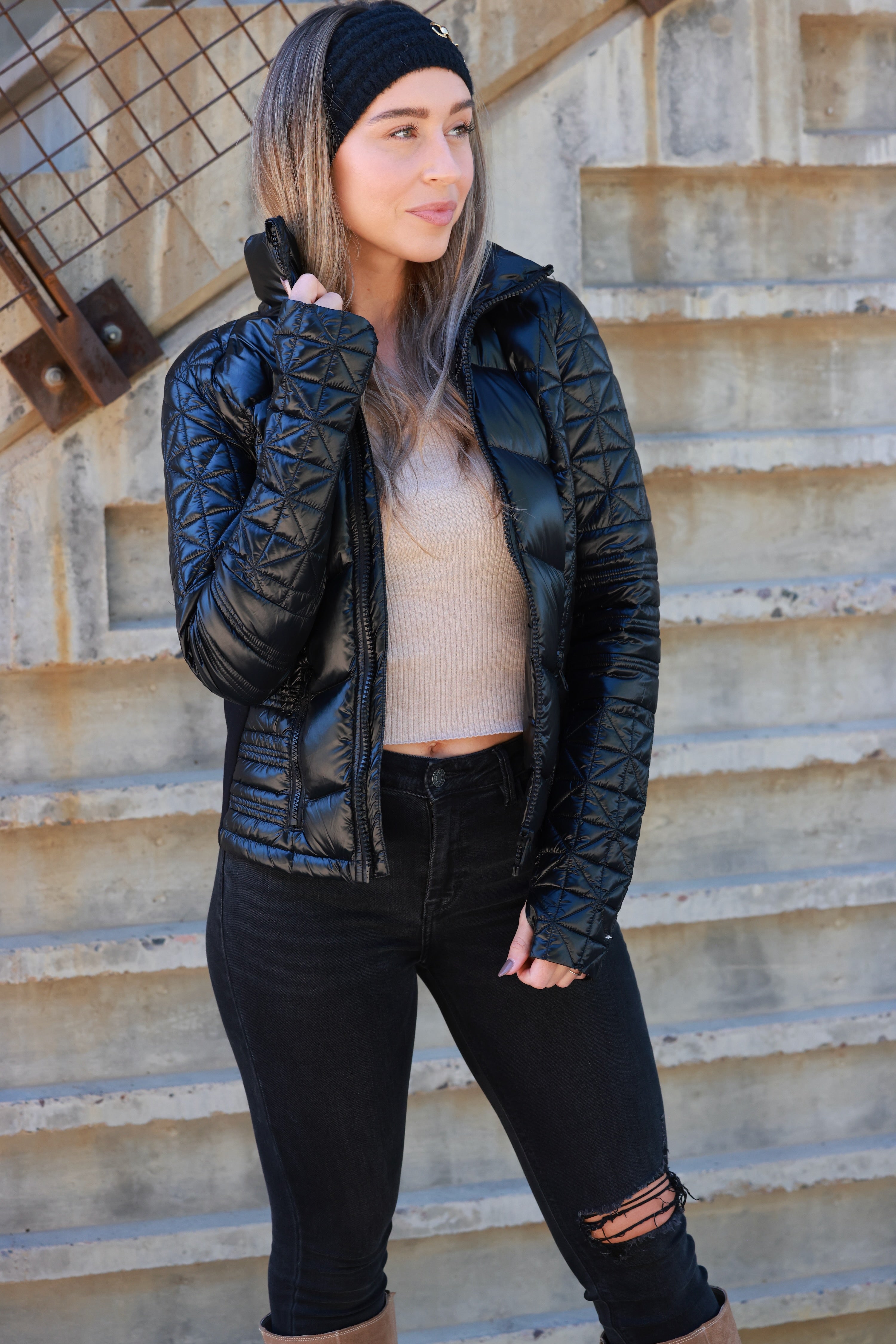 Woman wearing a black quilted jacket against a plain background - Packable puffer jacket, Lightweight down jacket, Black athletic outerwear, Travel-friendly puffer coat, Stylish winter layering