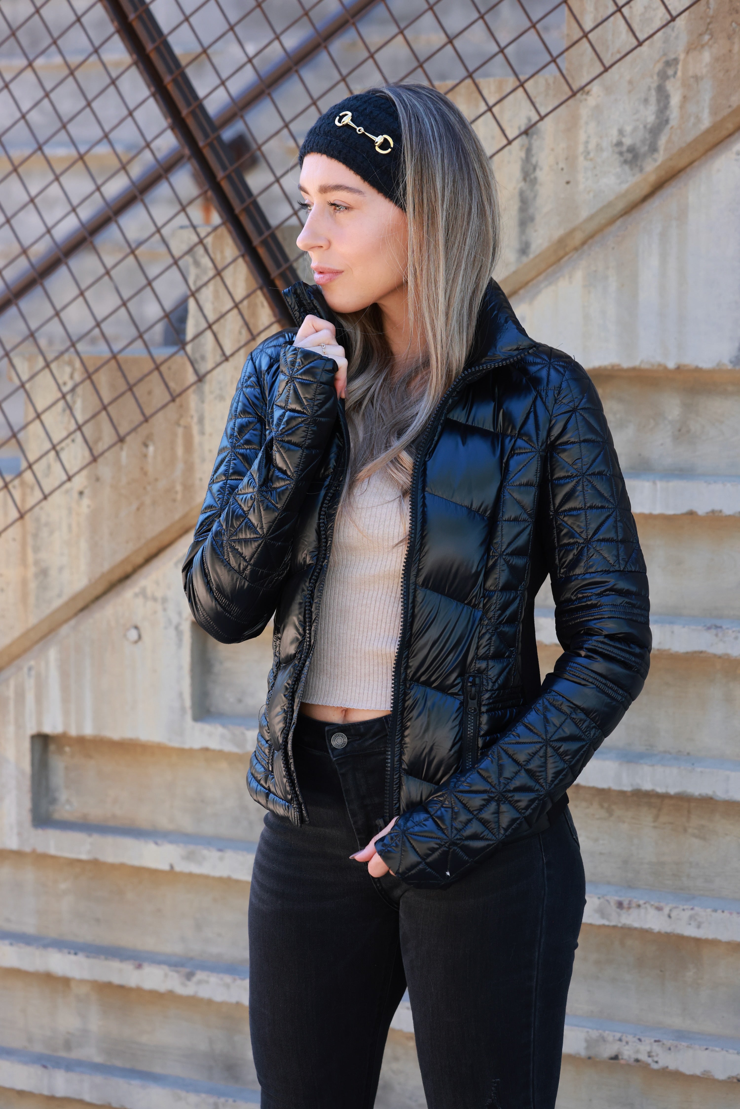 Woman wearing a black quilted jacket against a plain background - Packable puffer jacket, Lightweight down jacket, Black athletic outerwear, Travel-friendly puffer coat, Stylish winter layering