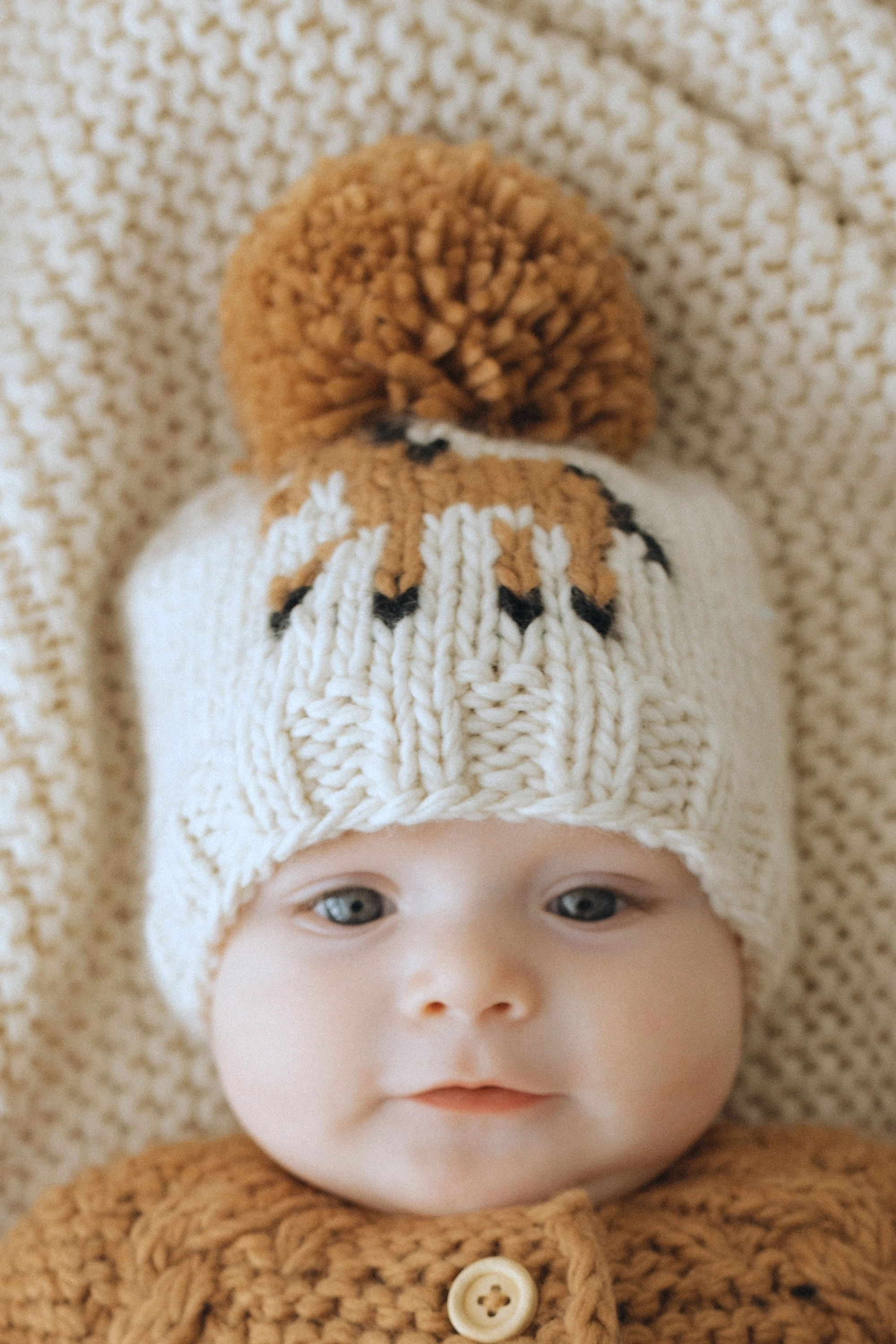 Hand-knit kids’ pony beanie in natural yarn with a pecan brown pony design on the front and a matching pecan pom-pom on top. Eco-friendly, sustainable equestrian-inspired winter hat for babies and children, made from recycled polyester and acrylic blend.