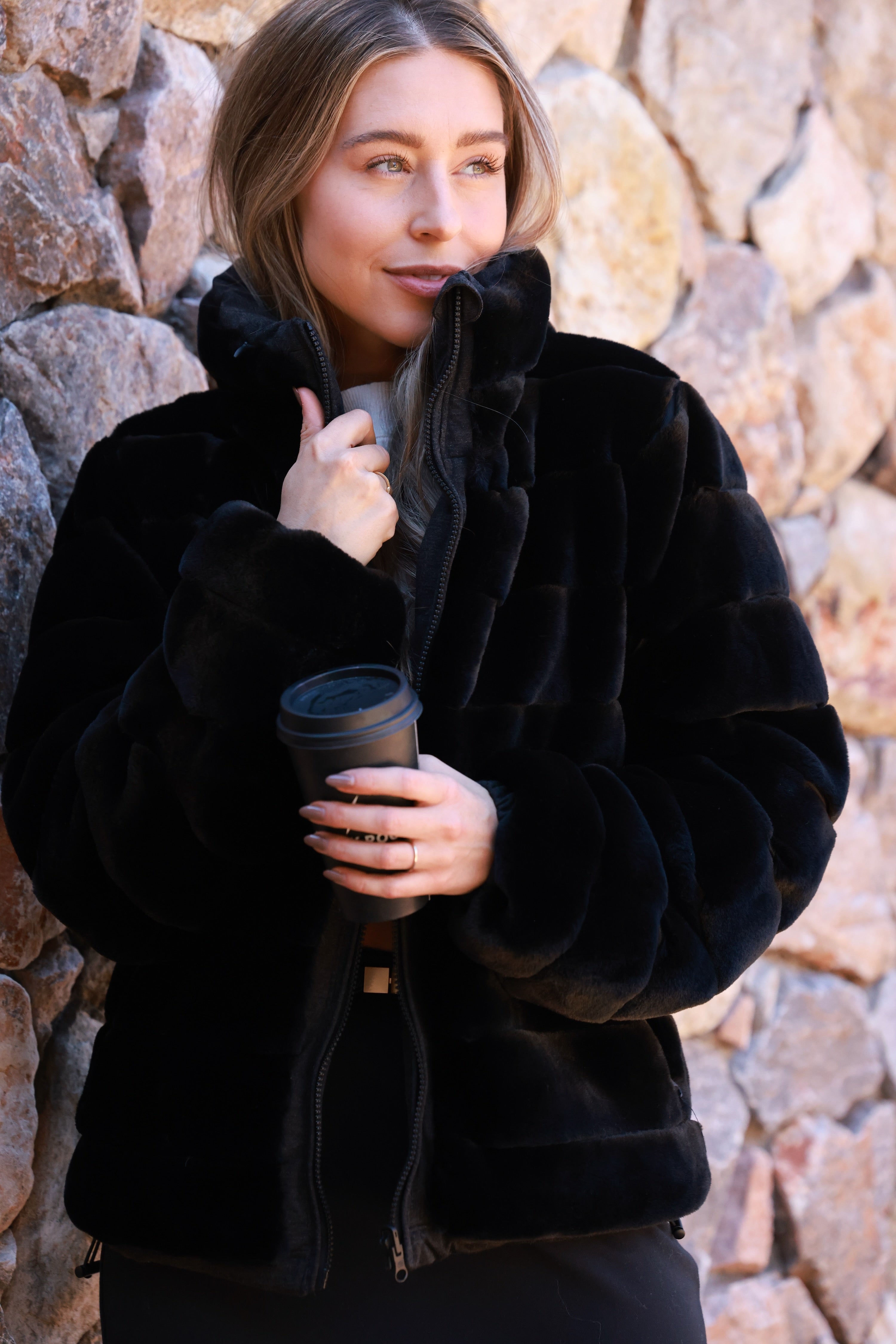 Black Reversible Puffer Jacket featuring a sleek exterior and ultra-soft faux fur interior for versatile styling. Down-filled for warmth with adjustable drawstring waist, hidden hood, and thumbholes for comfort. A stylish, adventure-ready equestrian-inspired winter coat perfect from trails to town.