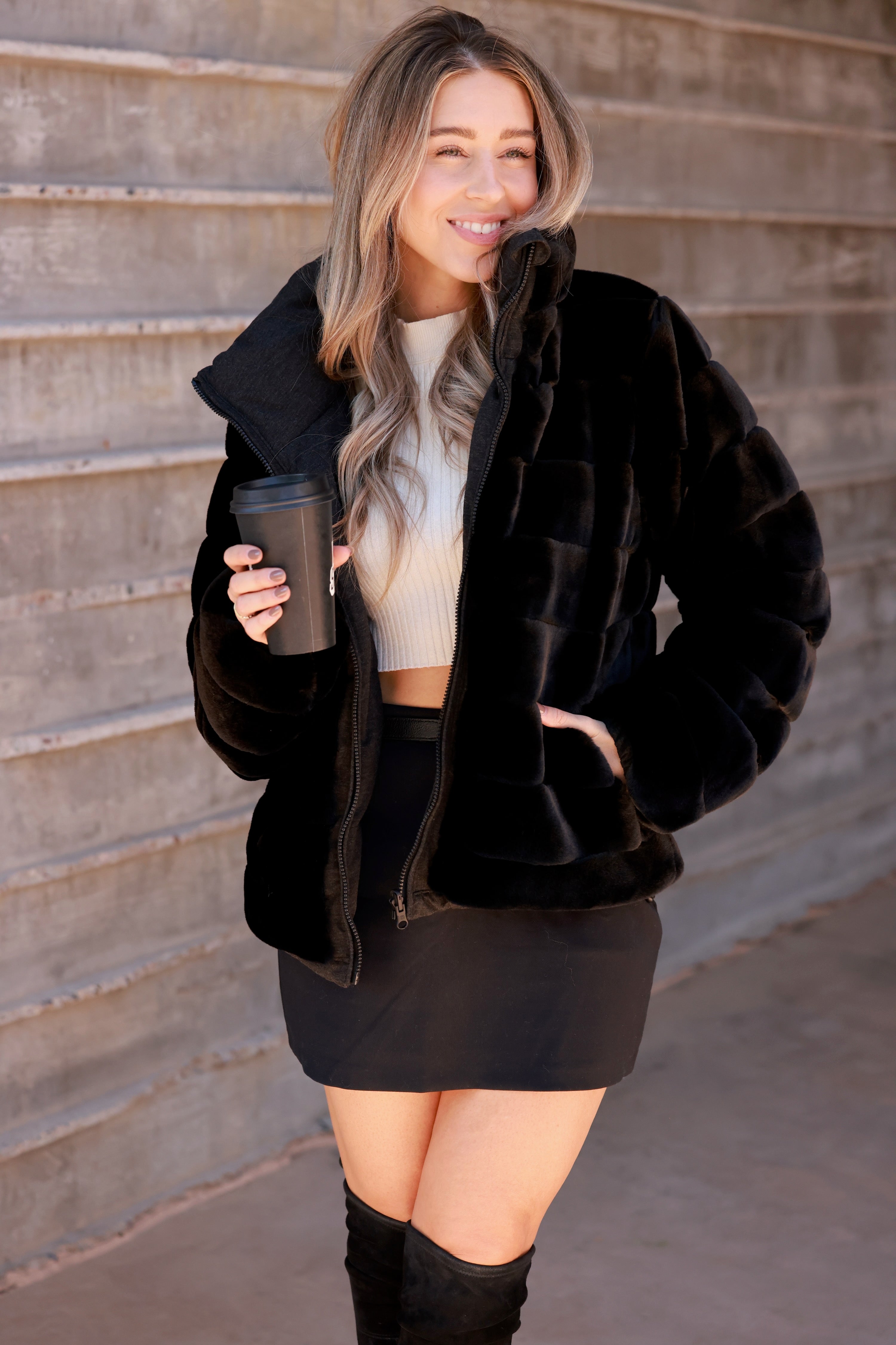 Black Reversible Puffer Jacket featuring a sleek exterior and ultra-soft faux fur interior for versatile styling. Down-filled for warmth with adjustable drawstring waist, hidden hood, and thumbholes for comfort. A stylish, adventure-ready equestrian-inspired winter coat perfect from trails to town.