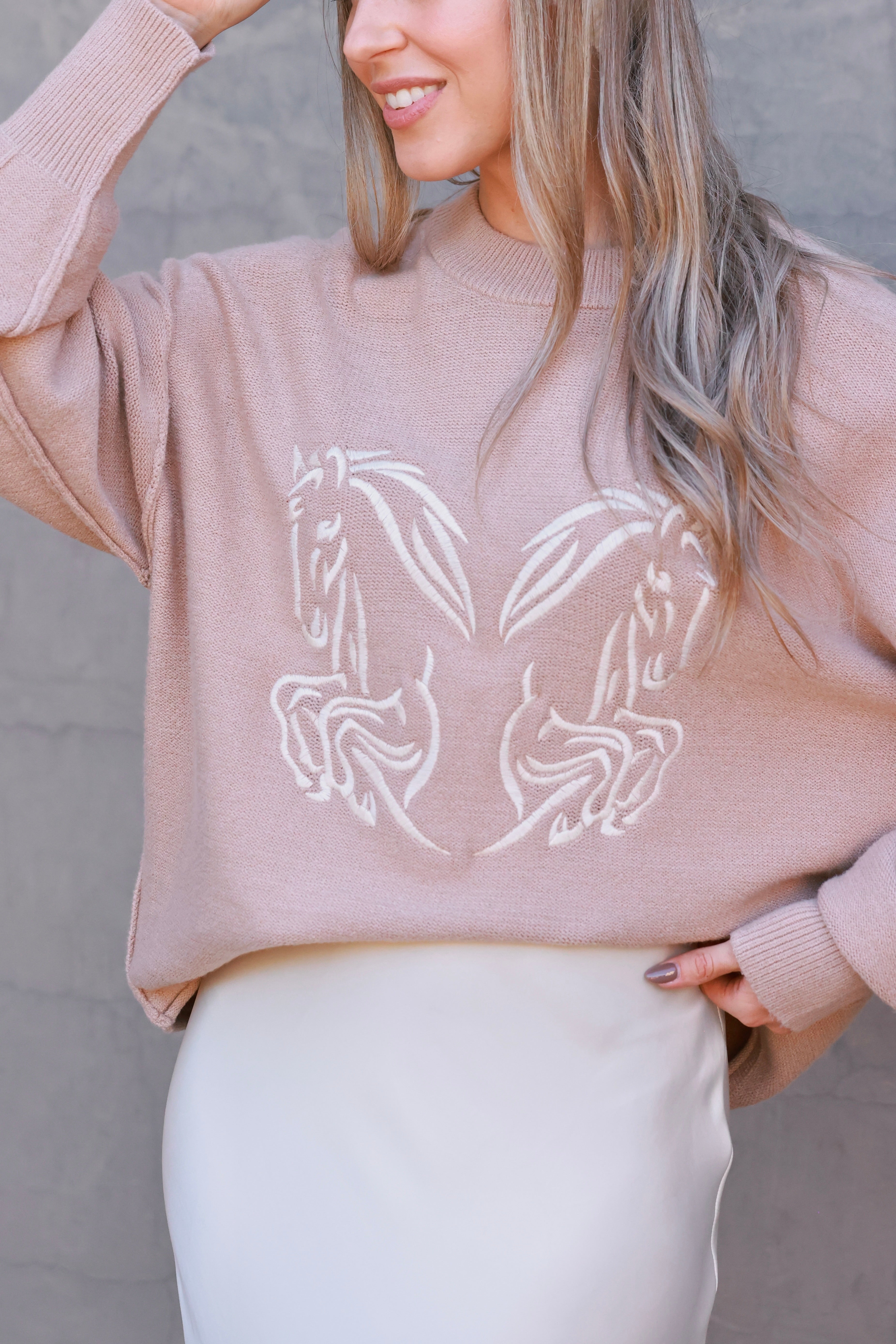 Roxy Embroidered Horse Sweater featuring tonal twin horse embroidery symbolizing strength and movement. Crafted from a soft viscose-poly-nylon blend with dropped shoulders, exposed seams, and side-split hem. A relaxed, minimalist equestrian sweater blending comfort and sophistication.