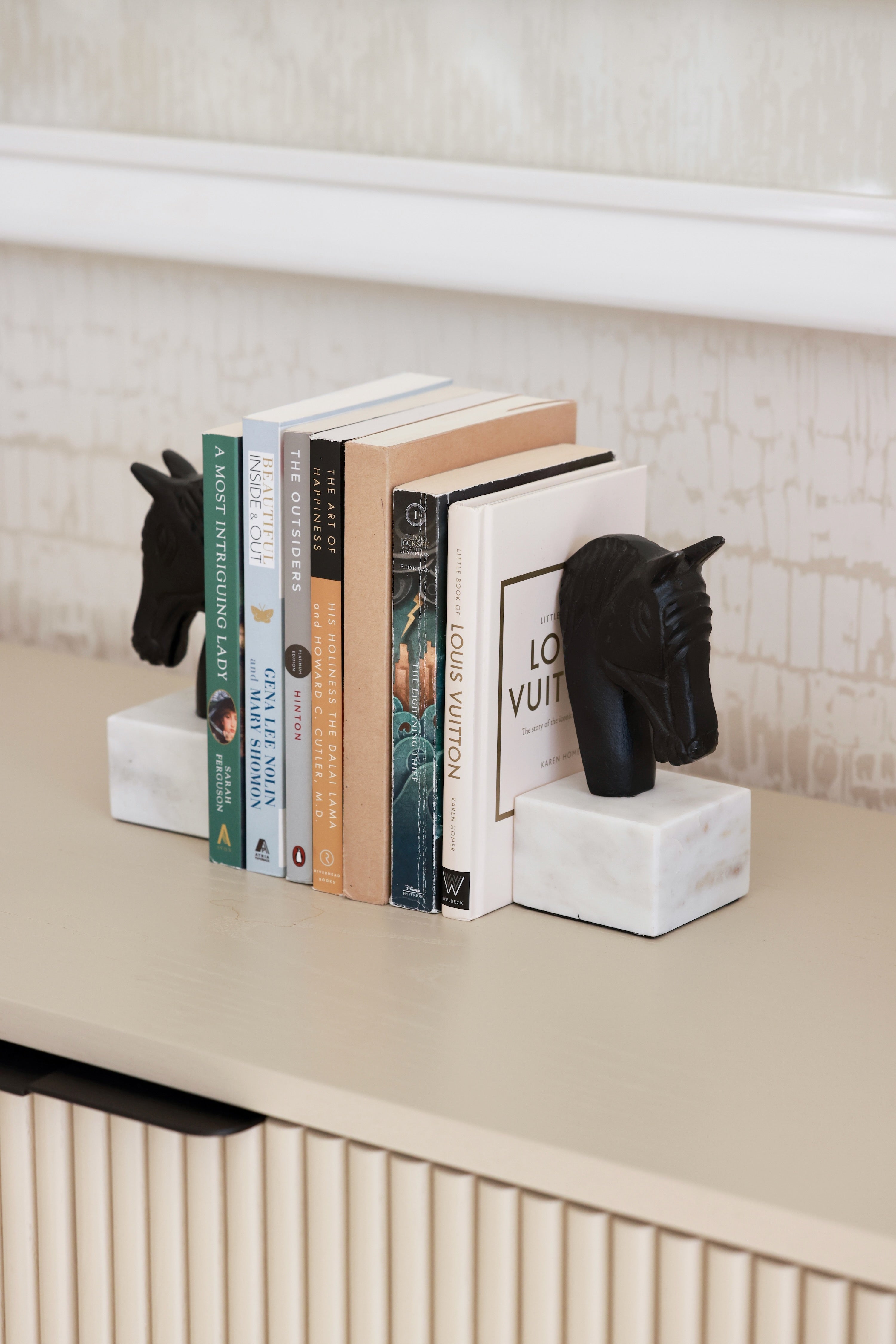Set of two metal horse head bookends with sleek black and white aluminum design and solid marble bases. Elegant equestrian-inspired home décor perfect for elevating a bookshelf, office, or home library while securely holding books with timeless style.