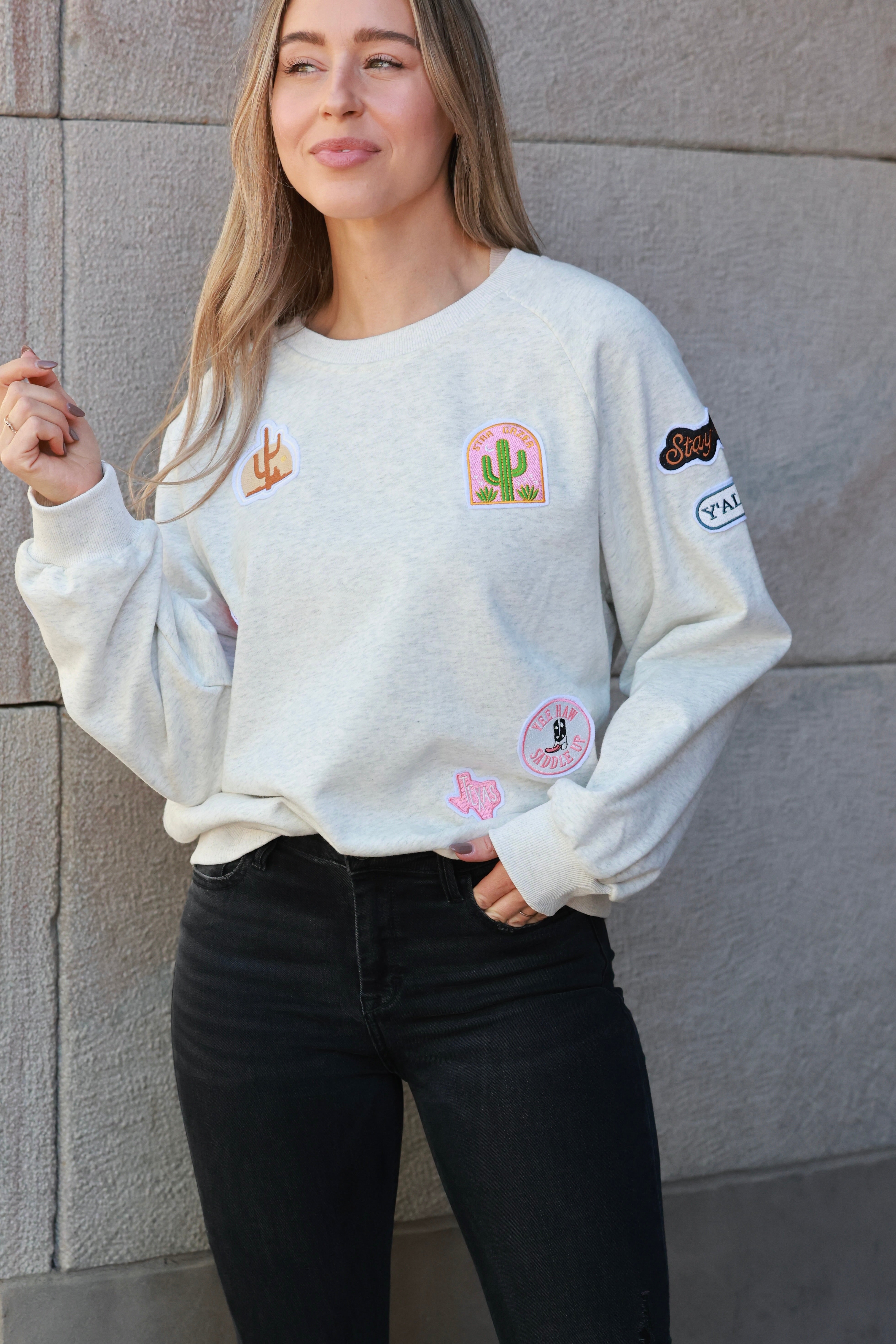 Stay Wild Patch Sweatshirt crafted from soft cotton with raglan sleeves and ribbed cuffs, neck, and hemline. Features a curated mix of western-inspired patches for a bold, adventurous equestrian look. True to size with an optional oversized fit for casual horse-girl style.