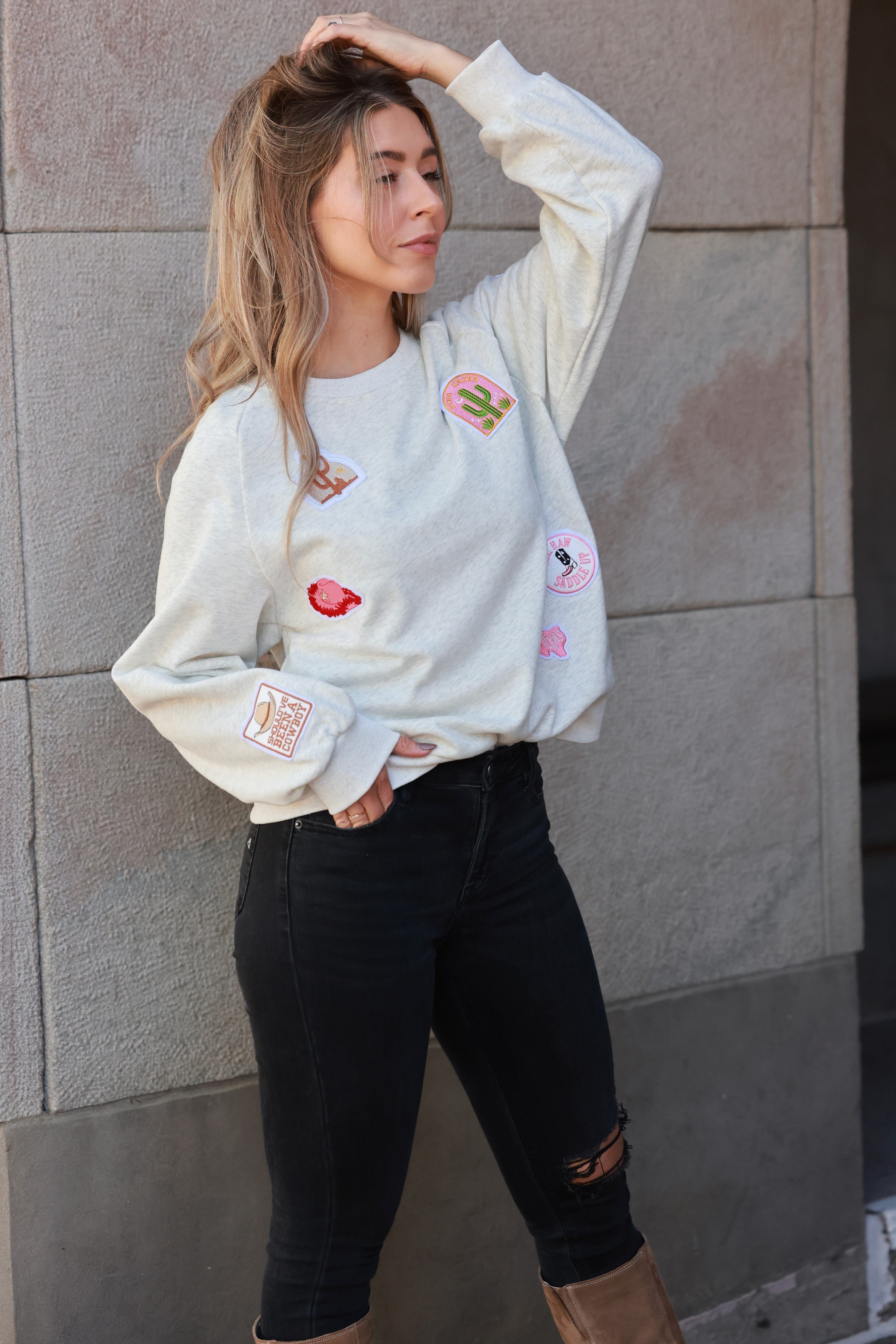 Stay Wild Patch Sweatshirt crafted from soft cotton with raglan sleeves and ribbed cuffs, neck, and hemline. Features a curated mix of western-inspired patches for a bold, adventurous equestrian look. True to size with an optional oversized fit for casual horse-girl style.