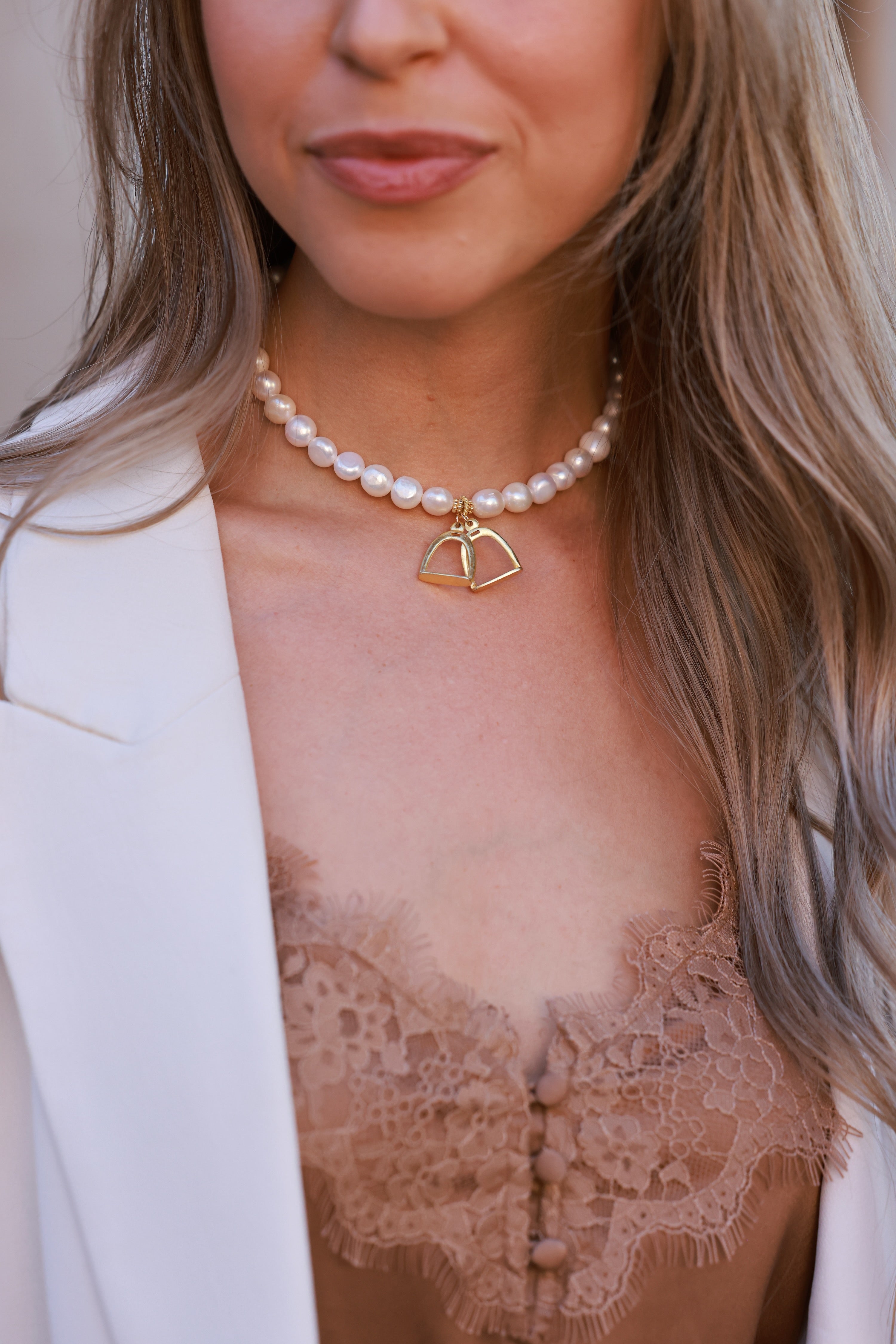 A refined fusion of equestrian charm and classic beauty. The Stirrup Pearl Necklace features lightweight stirrup accents delicately linked between lustrous pearls. Perfect for everyday elegance or layering. Measures 15" with an adjustable extender.
