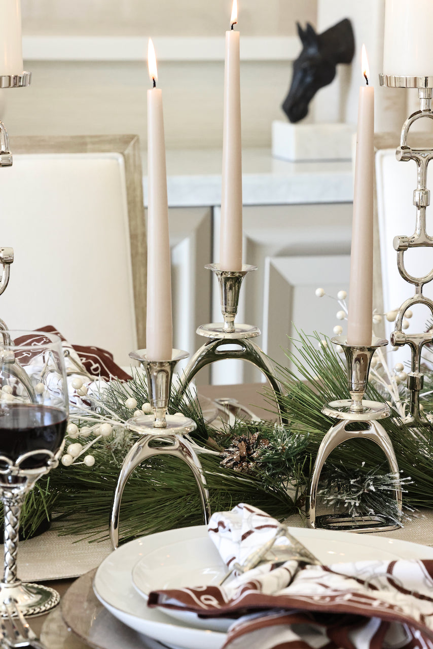 Silver Stirrup Candle Holder featuring a polished equestrian stirrup design that holds tapered candles. Available in small (6") and large (10") sizes, this elegant home accent adds refined equestrian charm to any space.