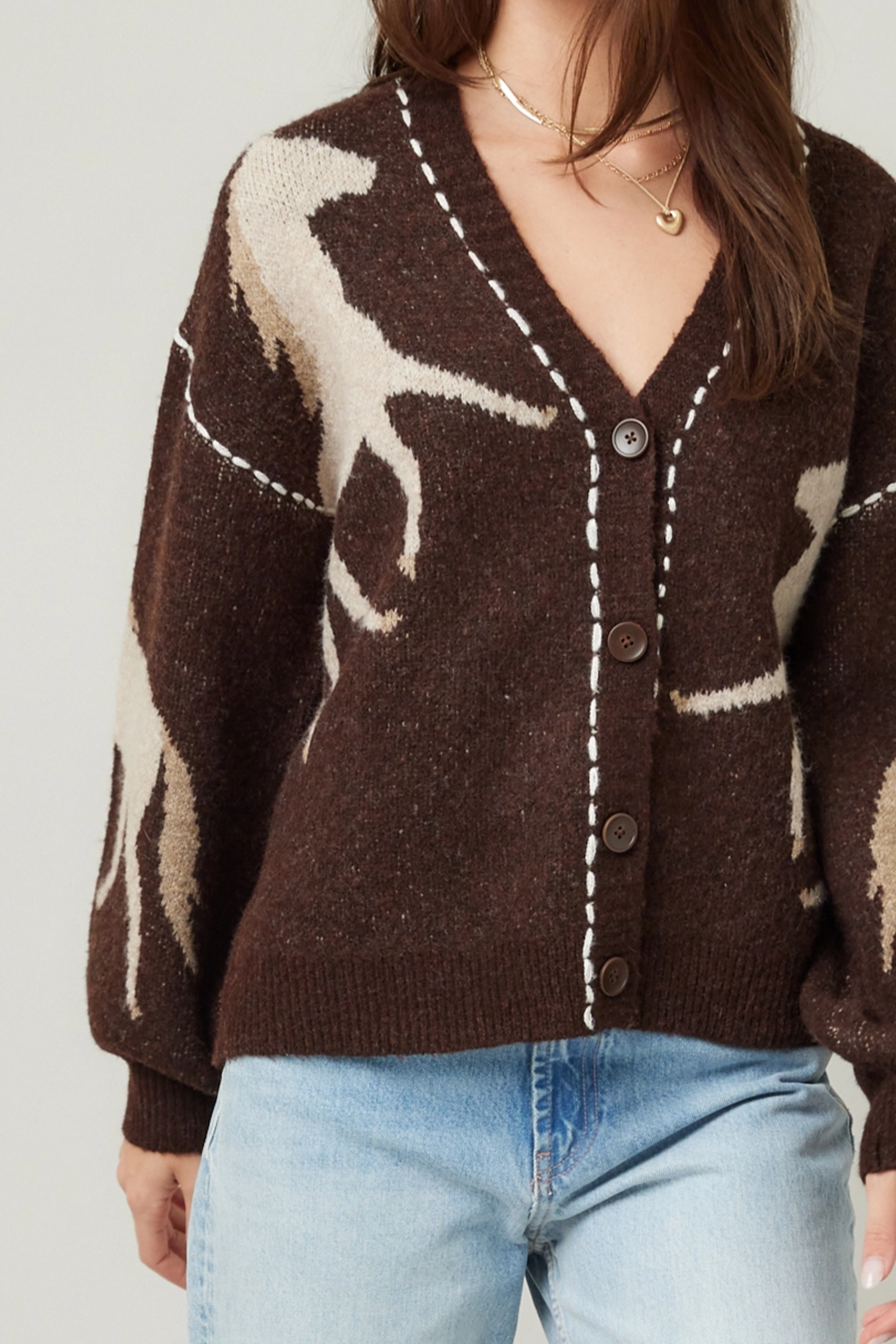 Woman wearing a brown cardigan with deer pattern and light blue jeans on a plain background - Horse knit cardigan, Brown western cardigan, Cowgirl graphic sweater, Oversized horse print cardigan, Equestrian boutique knitwear