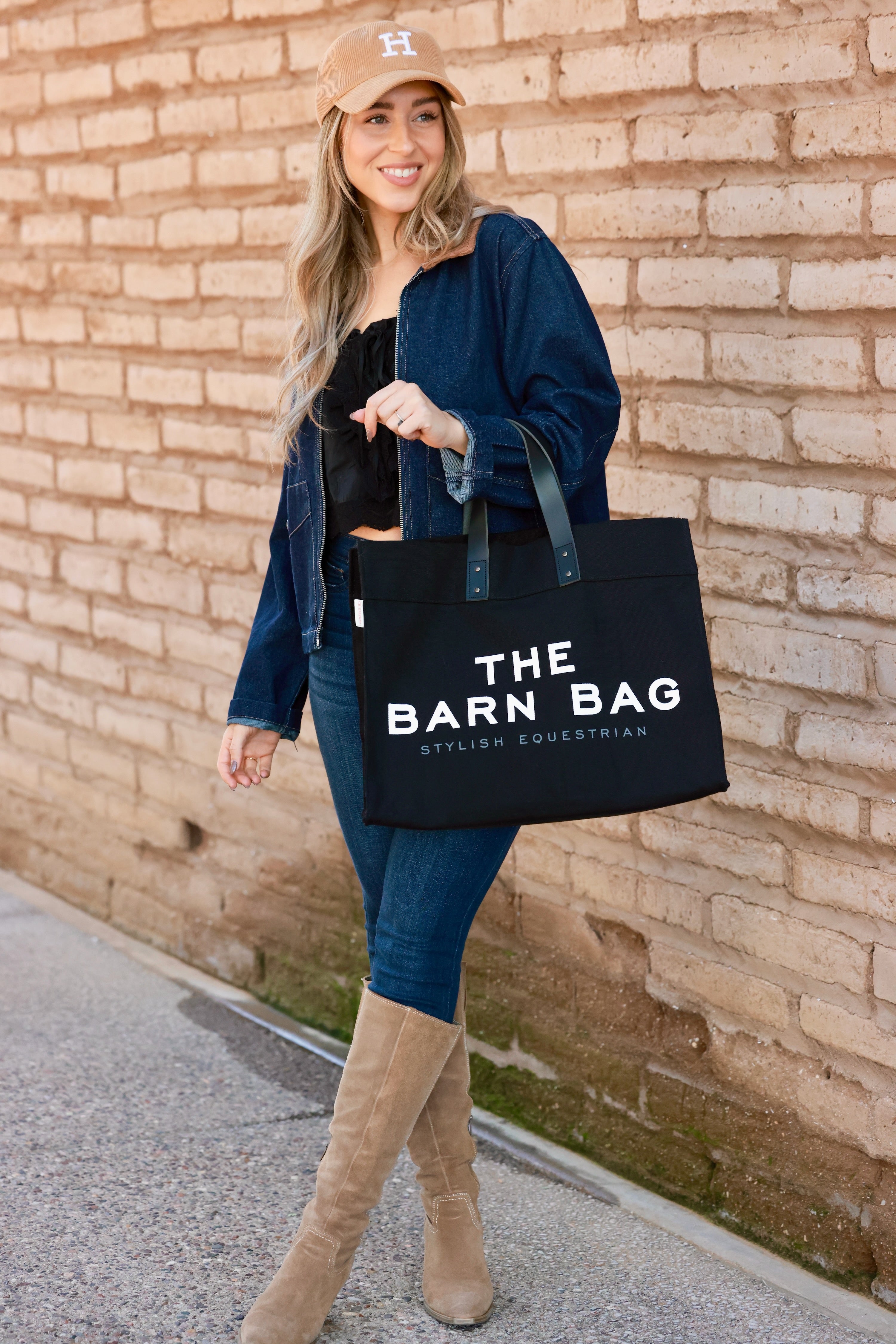 The Barn Bag Tote by Stylish Equestrian — durable canvas carry-all featuring cheeky front print, genuine leather handles, and two interior side pockets perfectly sized for a champagne bottle. Made in the USA, this equestrian-inspired tote is the ultimate barn and horse show essential.