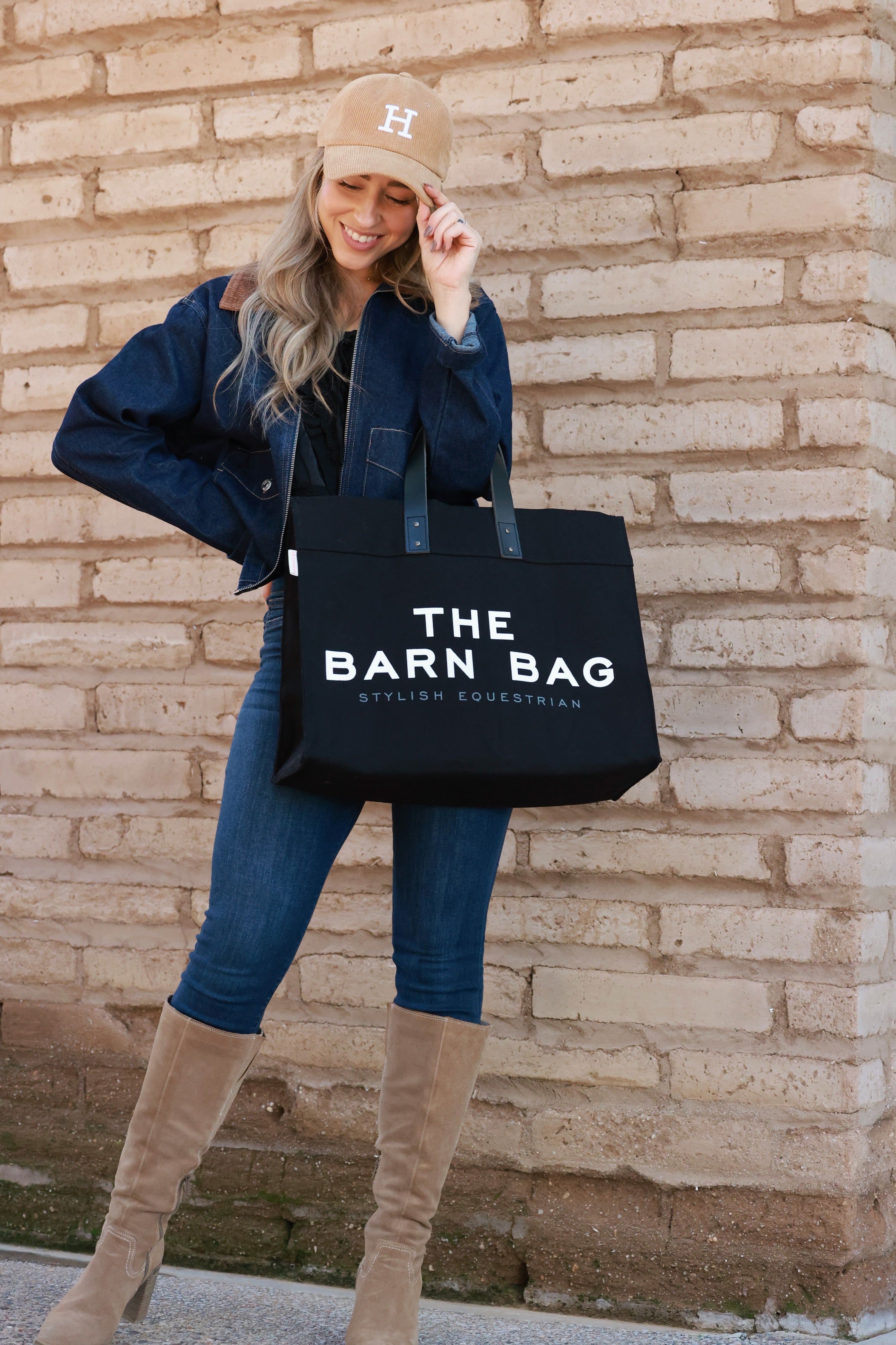 The Barn Bag Tote by Stylish Equestrian — durable canvas carry-all featuring cheeky front print, genuine leather handles, and two interior side pockets perfectly sized for a champagne bottle. Made in the USA, this equestrian-inspired tote is the ultimate barn and horse show essential.