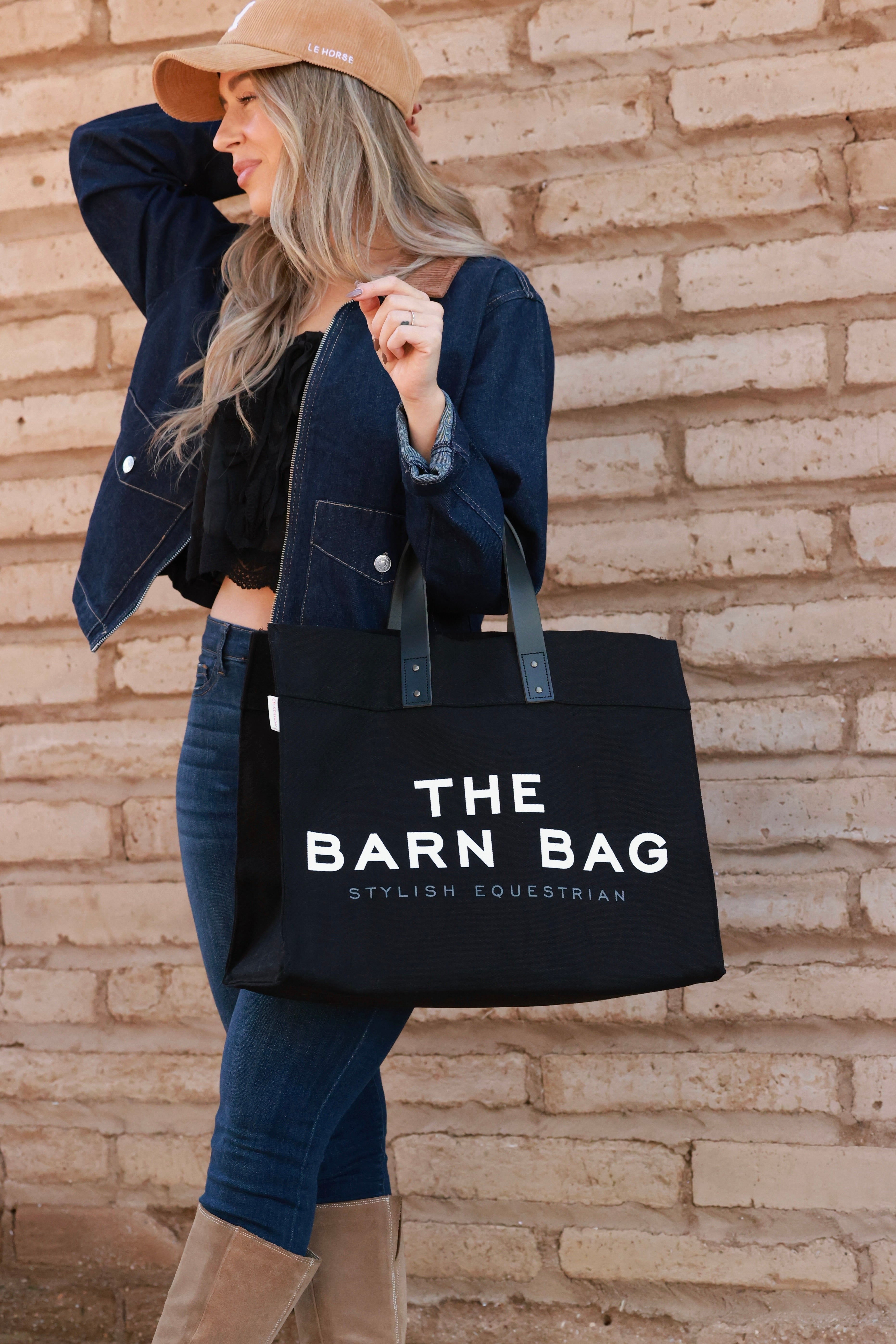 The Barn Bag Tote by Stylish Equestrian — durable canvas carry-all featuring cheeky front print, genuine leather handles, and two interior side pockets perfectly sized for a champagne bottle. Made in the USA, this equestrian-inspired tote is the ultimate barn and horse show essential.
