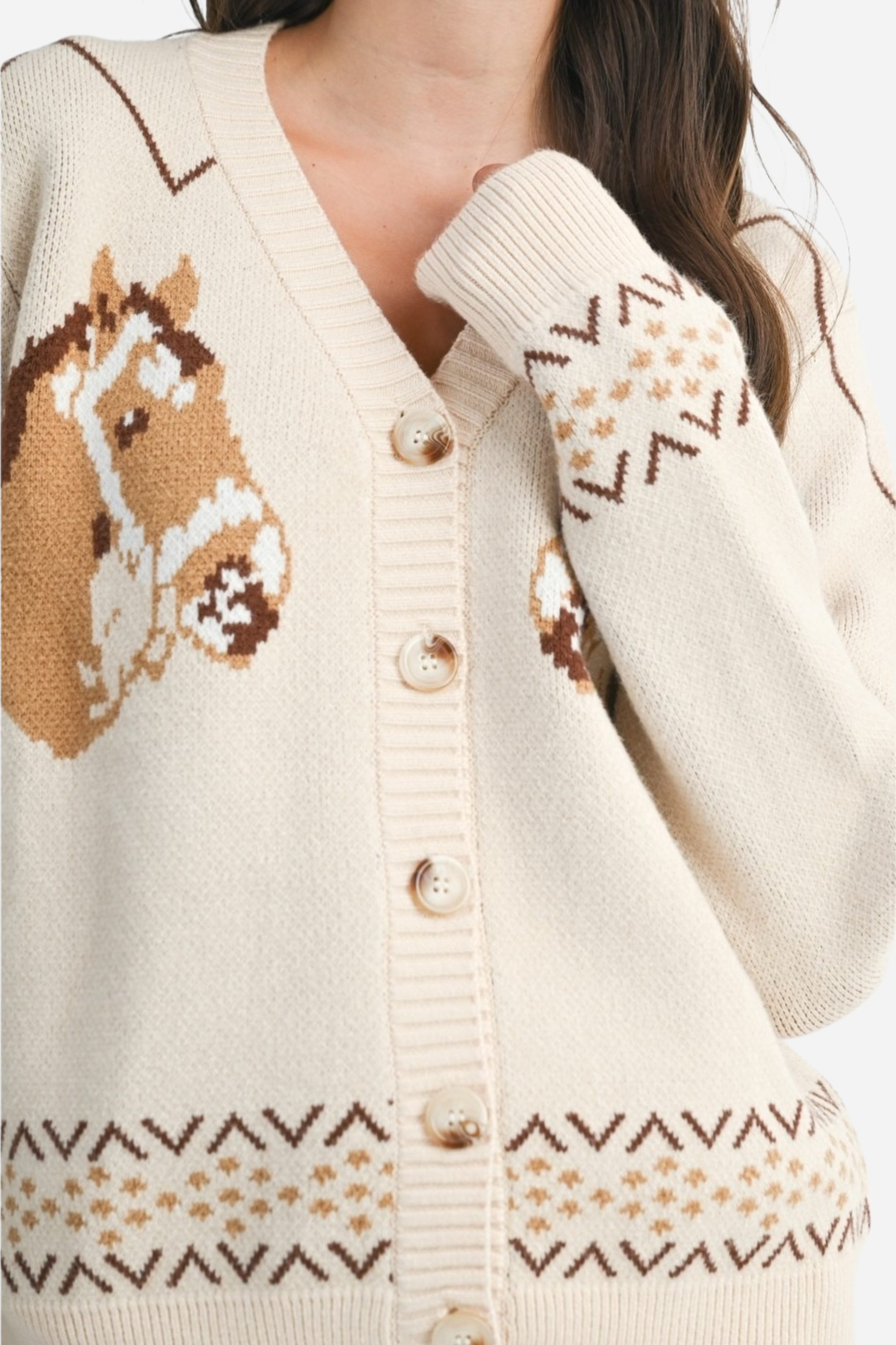 A cozy cream-colored knit cardigan with two brown horse graphics and subtle geometric fair isle trim. This long-sleeve, V-neck button-down features a relaxed, slightly cropped fit and soft viscose-poly blend fabric, offering a playful, equestrian-inspired look perfect for fall.