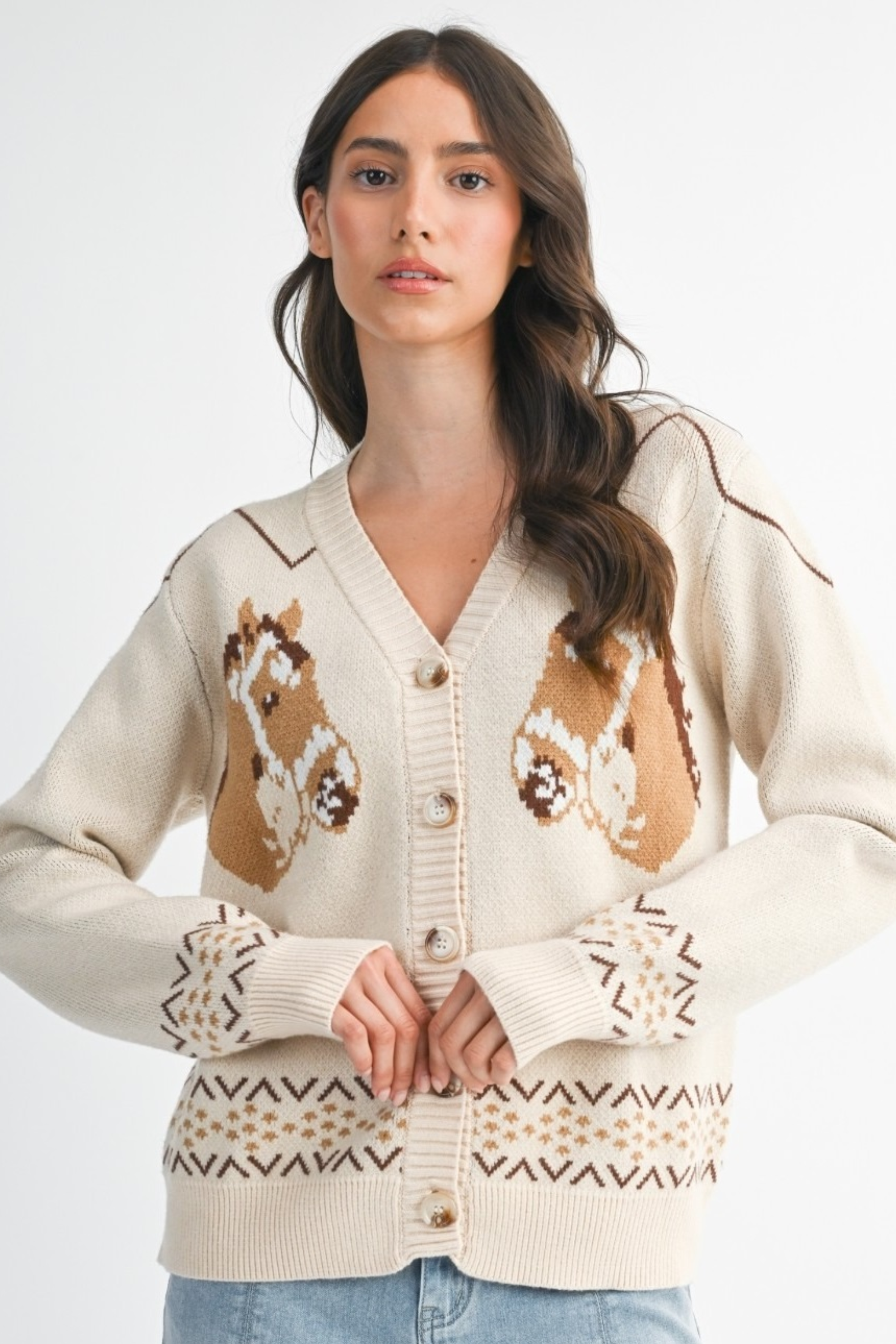 A cozy cream-colored knit cardigan with two brown horse graphics and subtle geometric fair isle trim. This long-sleeve, V-neck button-down features a relaxed, slightly cropped fit and soft viscose-poly blend fabric, offering a playful, equestrian-inspired look perfect for fall.