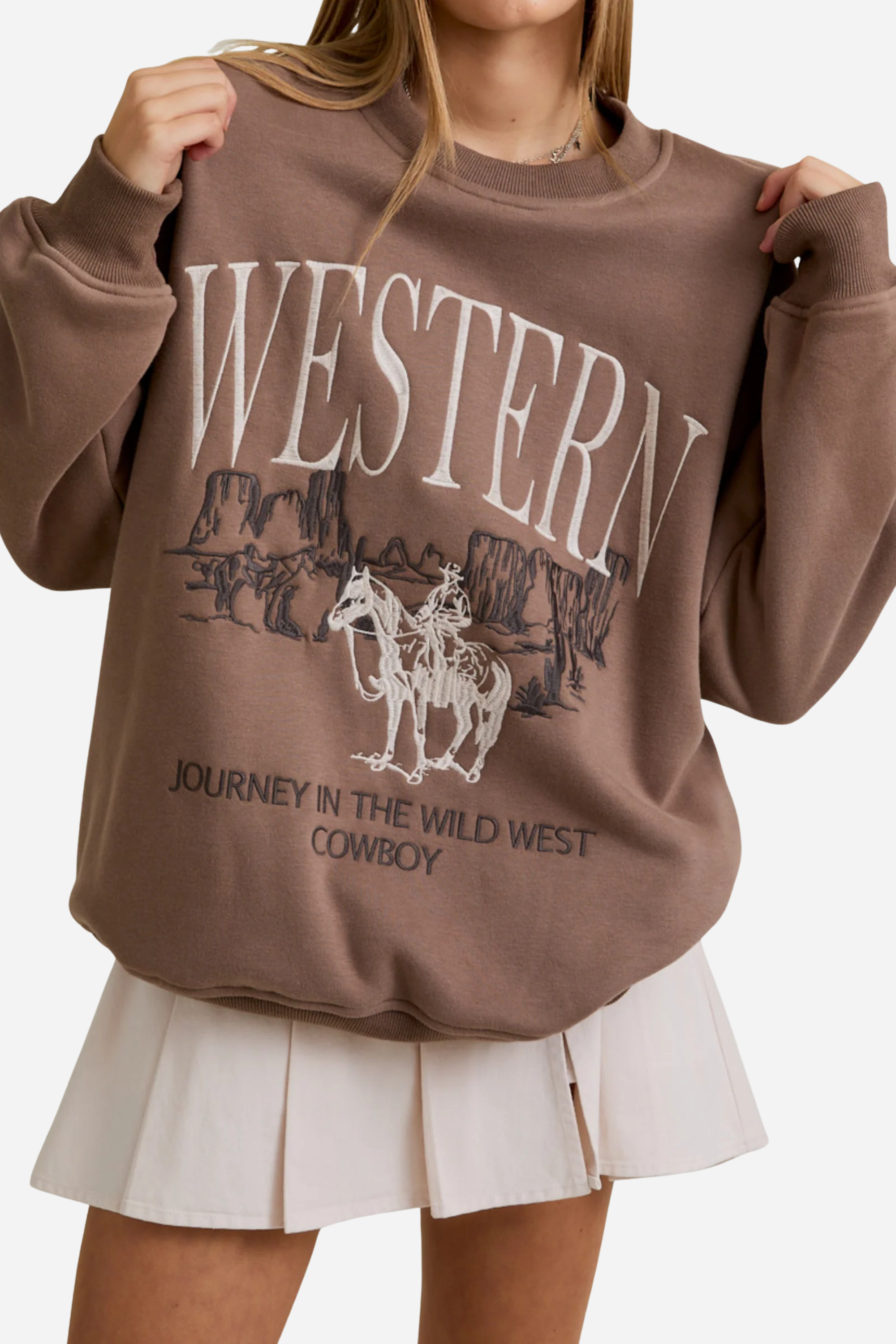 Brown sweatshirt with "WESTERN" in bold white letters, featuring an embroidered cowboy scene with cliffs. Text below reads, "JOURNEY IN THE WILD WEST COWBOY." western graphic sweatshirt, cowboy embroidered sweatshirt, women’s western fashion, vintage cowboy crewneck, casual western outfit, adventure inspired sweatshirt, bold western text sweater, wild west cowboy top, rustic western streetwear
