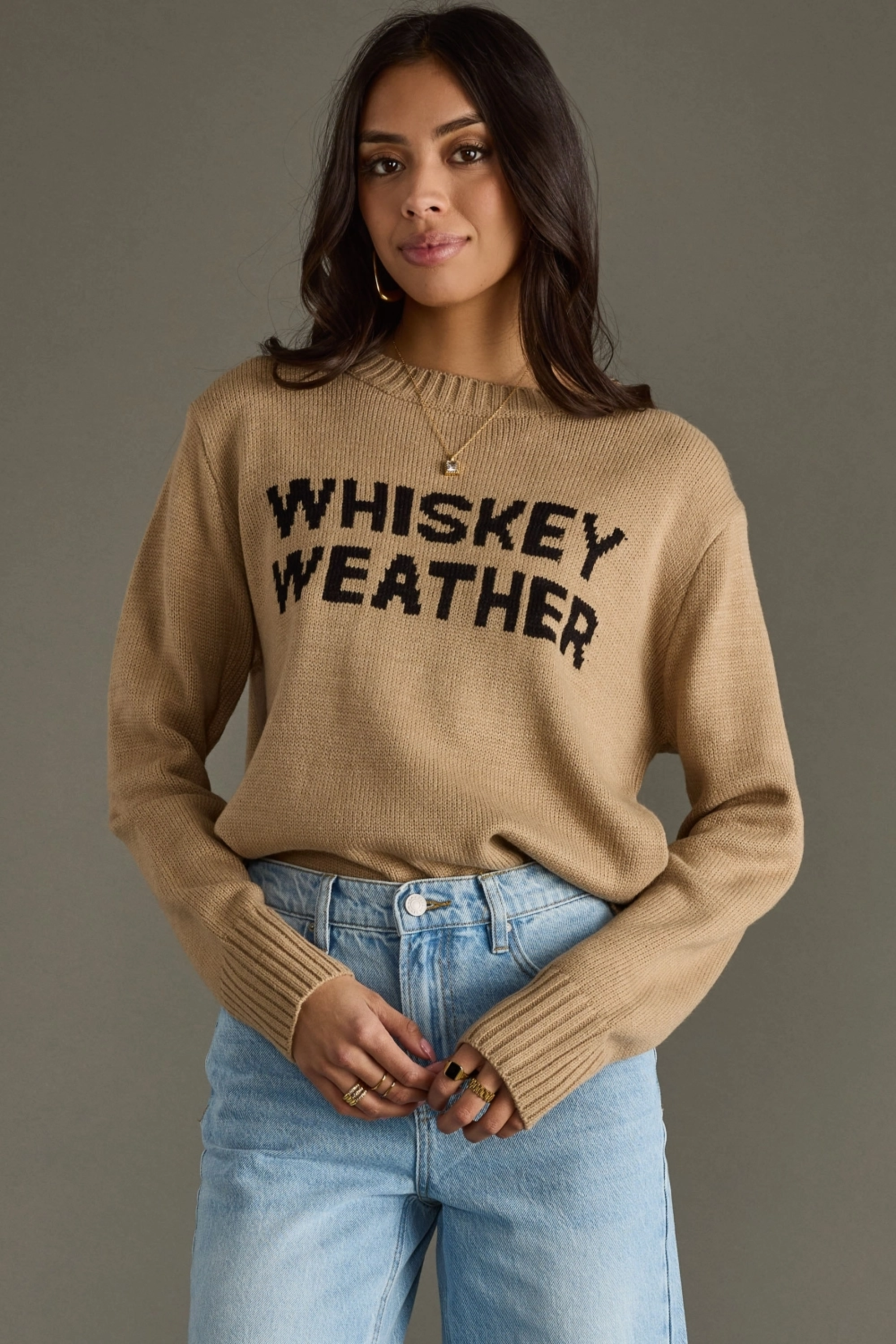 Woman wearing a beige sweater with 'WHISKEY WEATHER' text against a gray background - Whiskey weather sweater, Western graphic sweater, Fall country sweater, Taupe knit pullover, Cowgirl whiskey sweater