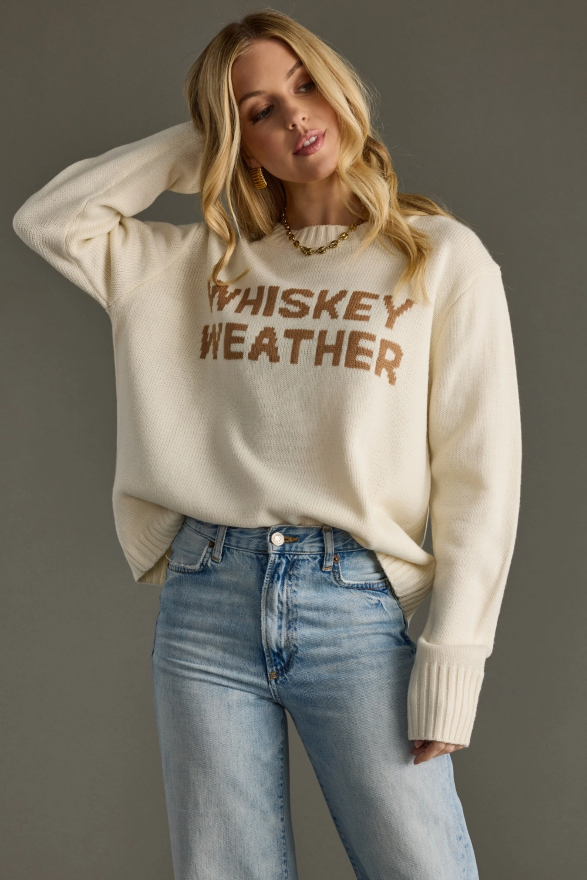 Woman wearing a beige sweater with 'WHISKEY WEATHER' text against a gray background - Whiskey weather sweater, Western graphic sweater, Fall country sweater, Ivory knit pullover, Cowgirl whiskey sweater