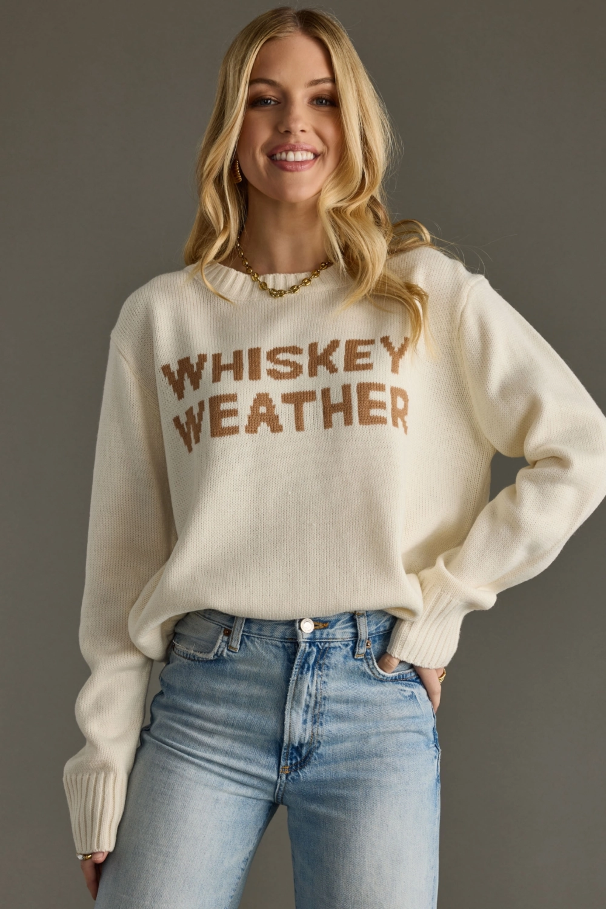 Woman wearing a beige sweater with 'WHISKEY WEATHER' text against a gray background - Whiskey weather sweater, Western graphic sweater, Fall country sweater, Ivory knit pullover, Cowgirl whiskey sweater