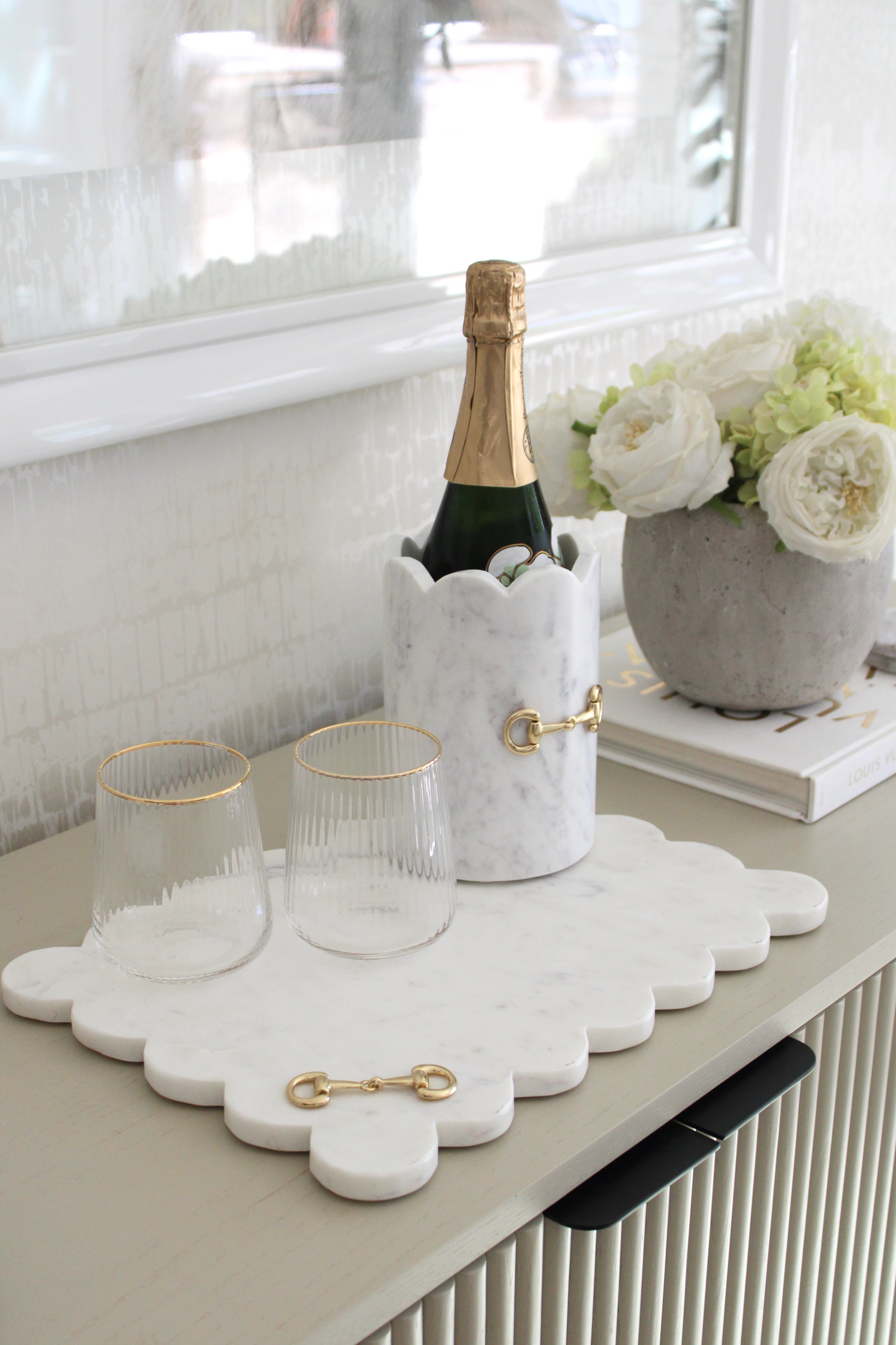 Luxurious white marble D-ring scalloped wine chiller with polished gold horse bit hardware, handcrafted for an elegant equestrian-inspired home. The cylindrical marble design features subtle natural veining, perfect for chilling wine or champagne, or as a stylish horse-themed vase or utensil holder.