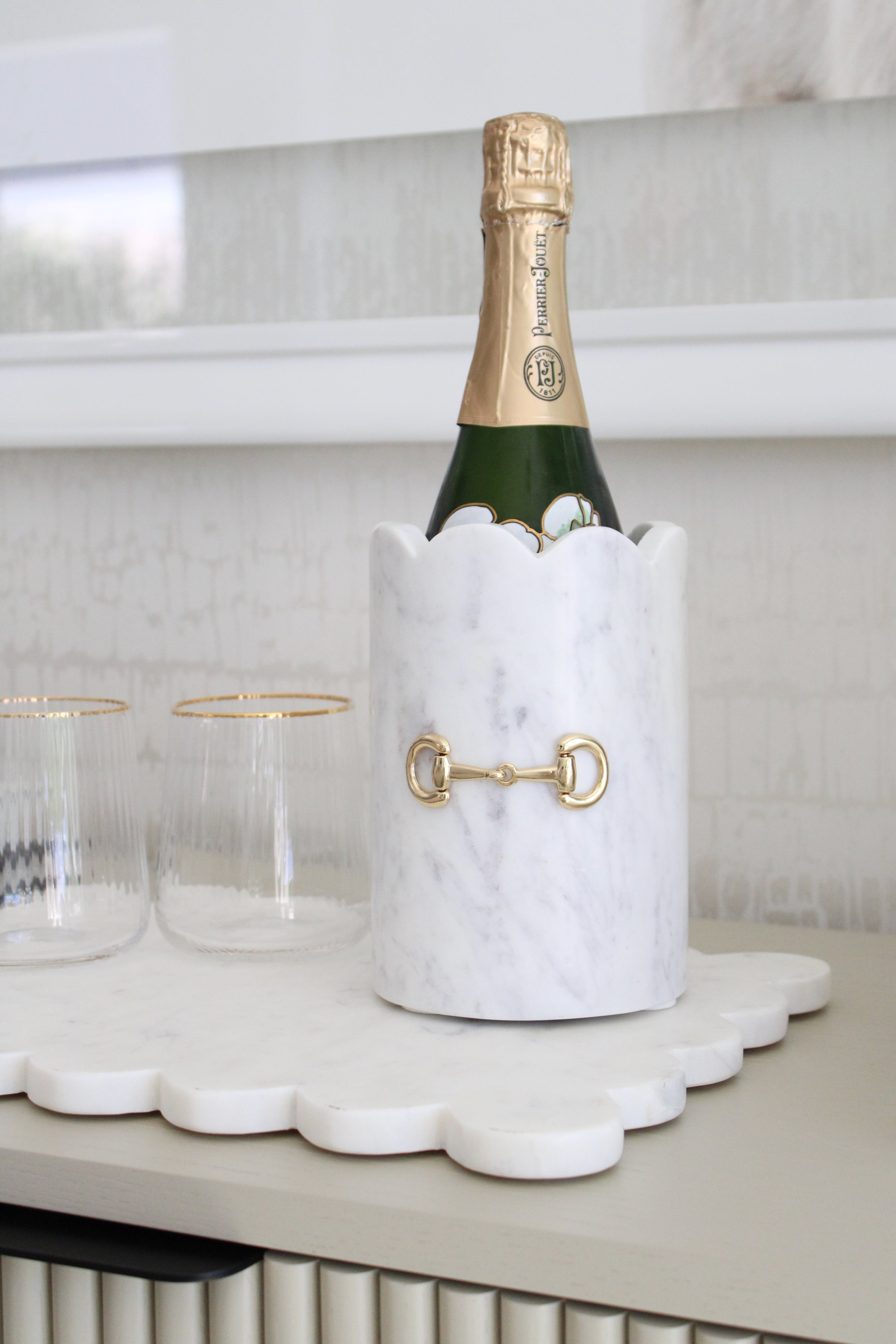Luxurious white marble D-ring scalloped wine chiller with polished gold horse bit hardware, handcrafted for an elegant equestrian-inspired home. The cylindrical marble design features subtle natural veining, perfect for chilling wine or champagne, or as a stylish horse-themed vase or utensil holder.