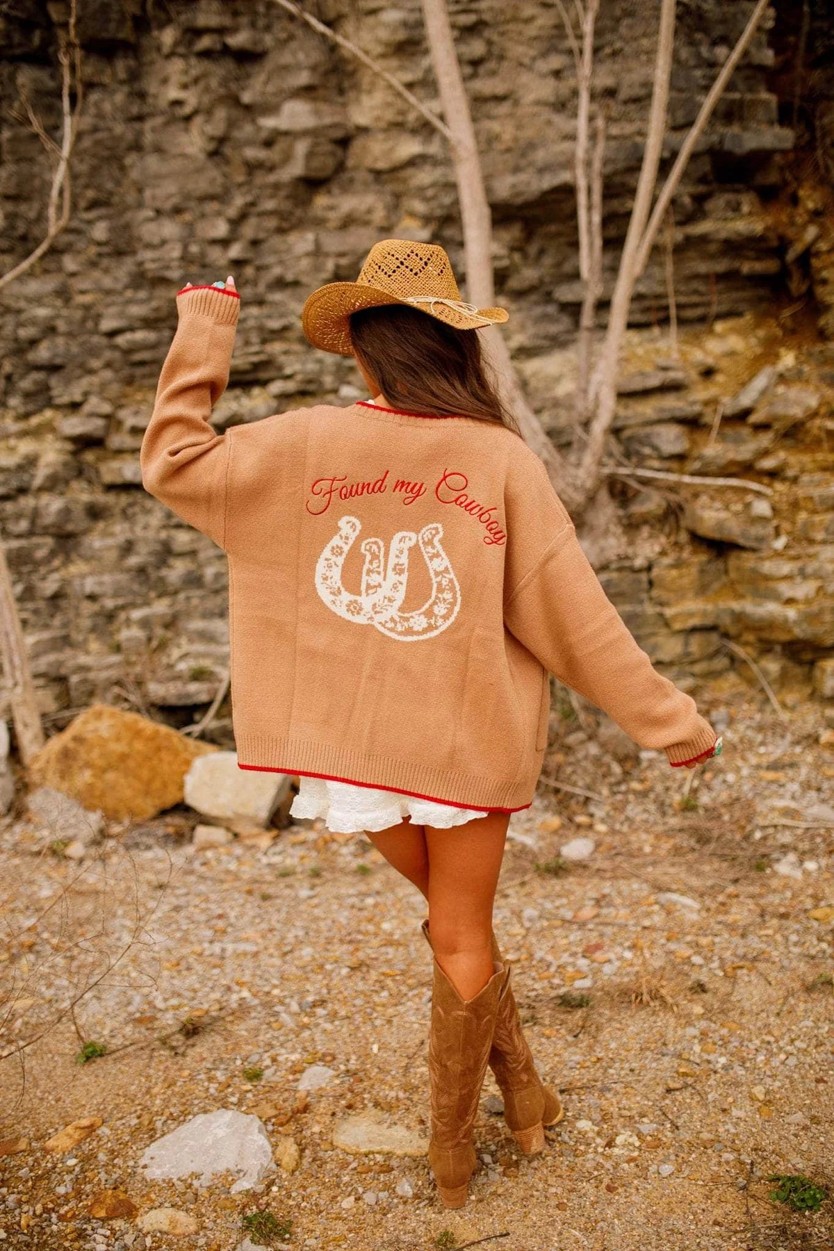 Person wearing a brown jacket with a horse and horseshoe design, standing in a rocky outdoor setting. - Western cardigan, Floral horseshoe sweater, Found my cowboy cardigan, Equestrian-inspired knitwear, Camel embroidered cardigan