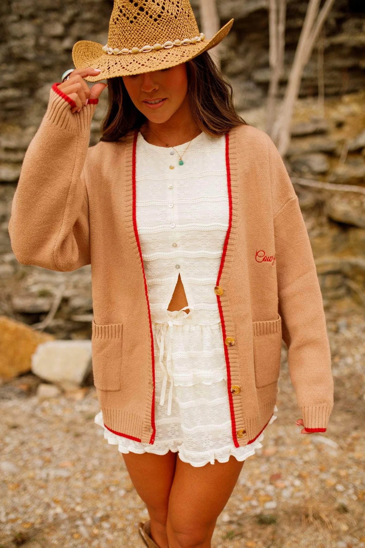 Woman wearing a beige cardigan with red trim, white dress, and straw hat outdoors. - Western cardigan, Floral horseshoe sweater, Found my cowboy cardigan, Equestrian-inspired knitwear, Camel embroidered cardigan